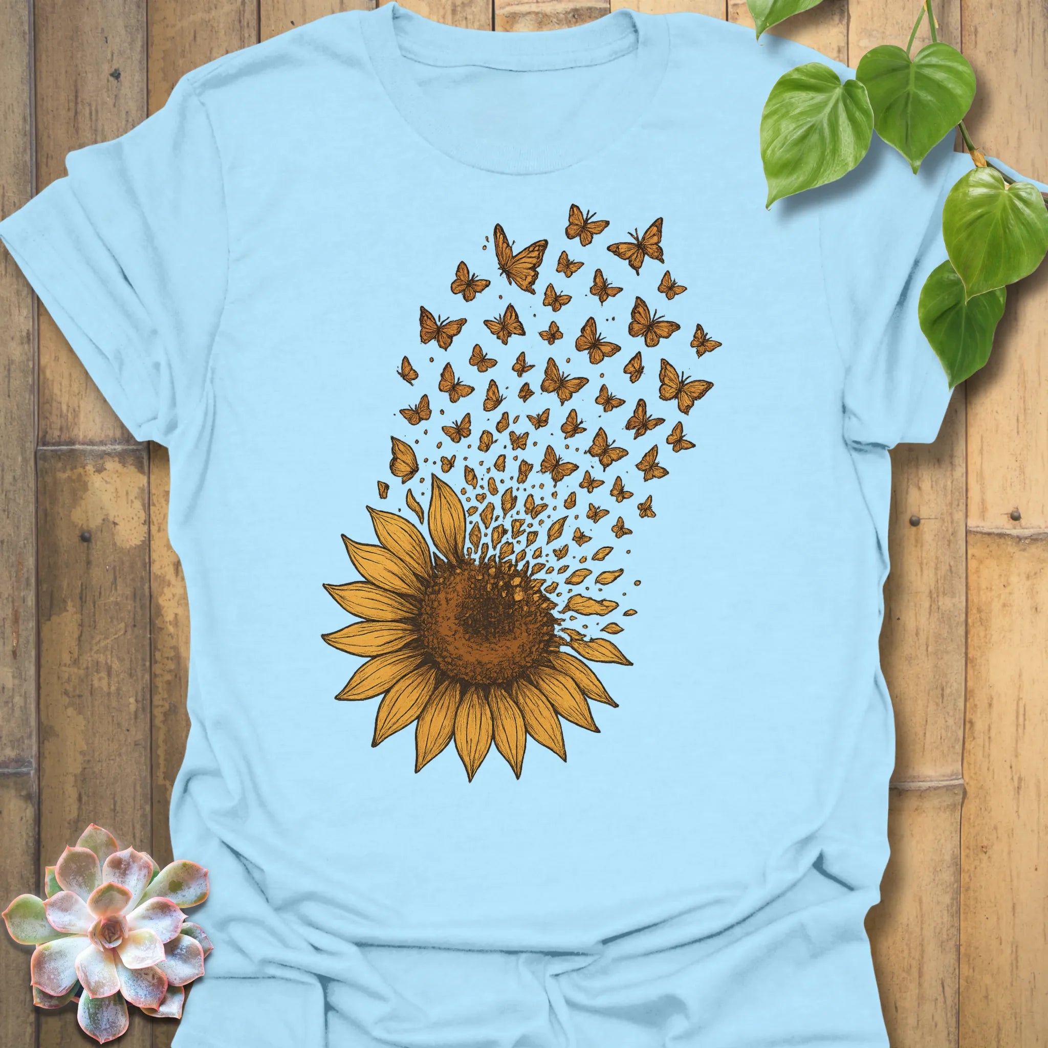 Let your spirit bloom in our Sunflower Butterfly tee — a calming light-blue shirt where golden petals transform into fluttering butterflies.