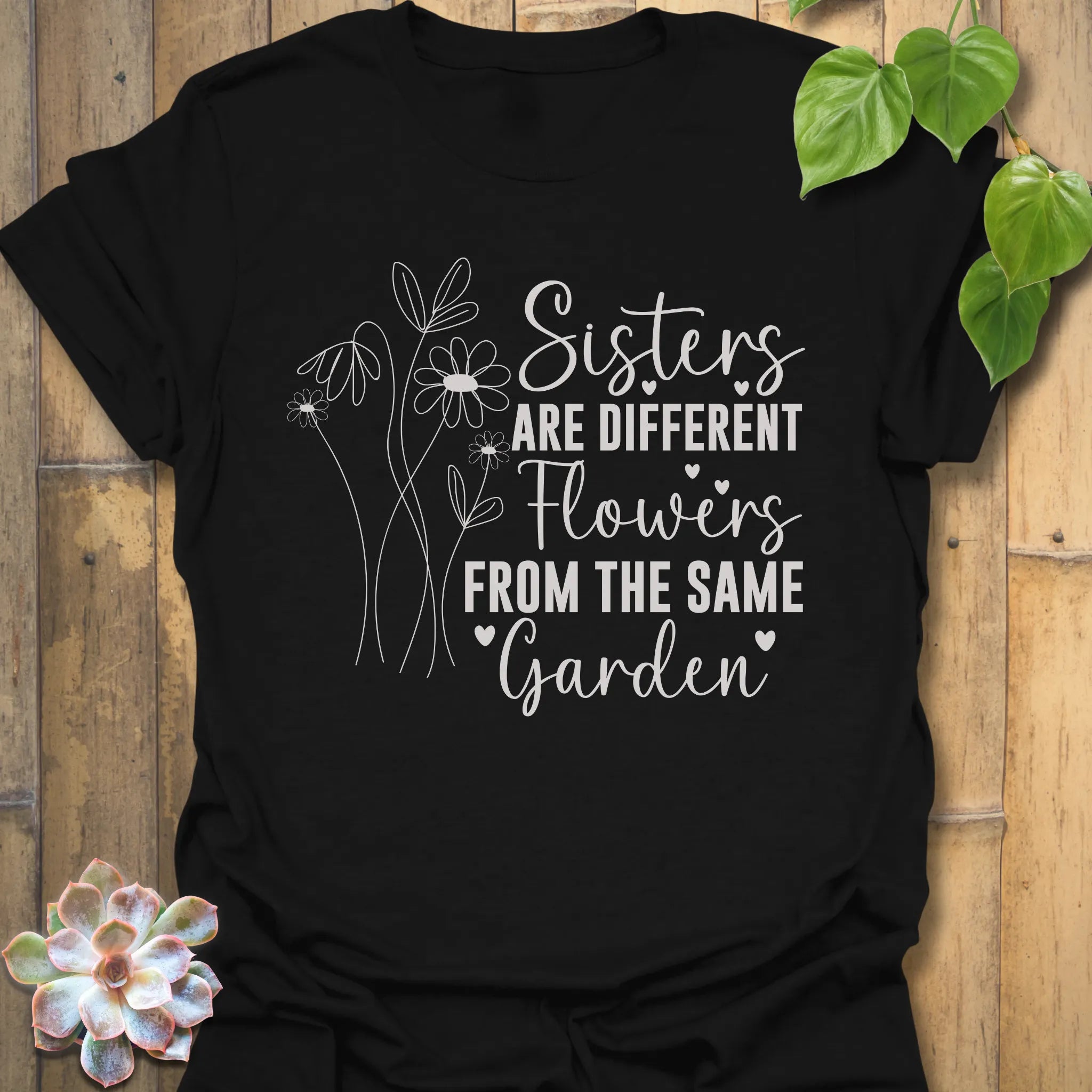 Black t-shirt with floral design with saying Sisters are different flowers from the same garden