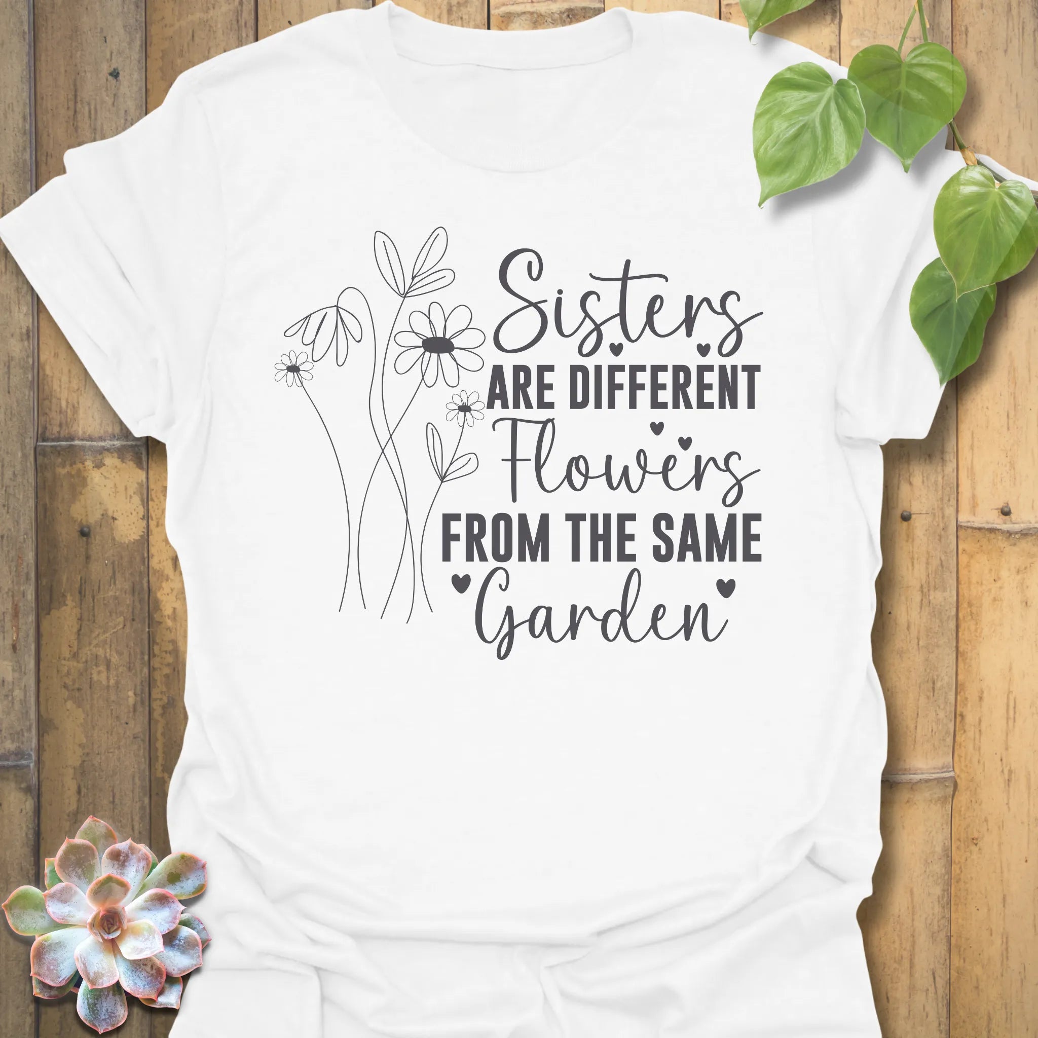 White t-shirt with floral design with saying Sisters are different flowers from the same garden