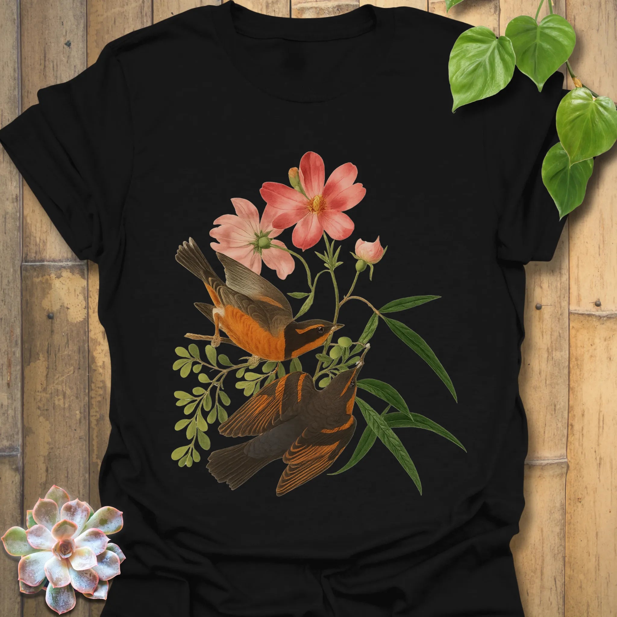 Black t-shirt featuring the Spring Songbirds design with two colourful birds perched among pink flowers and green leaves