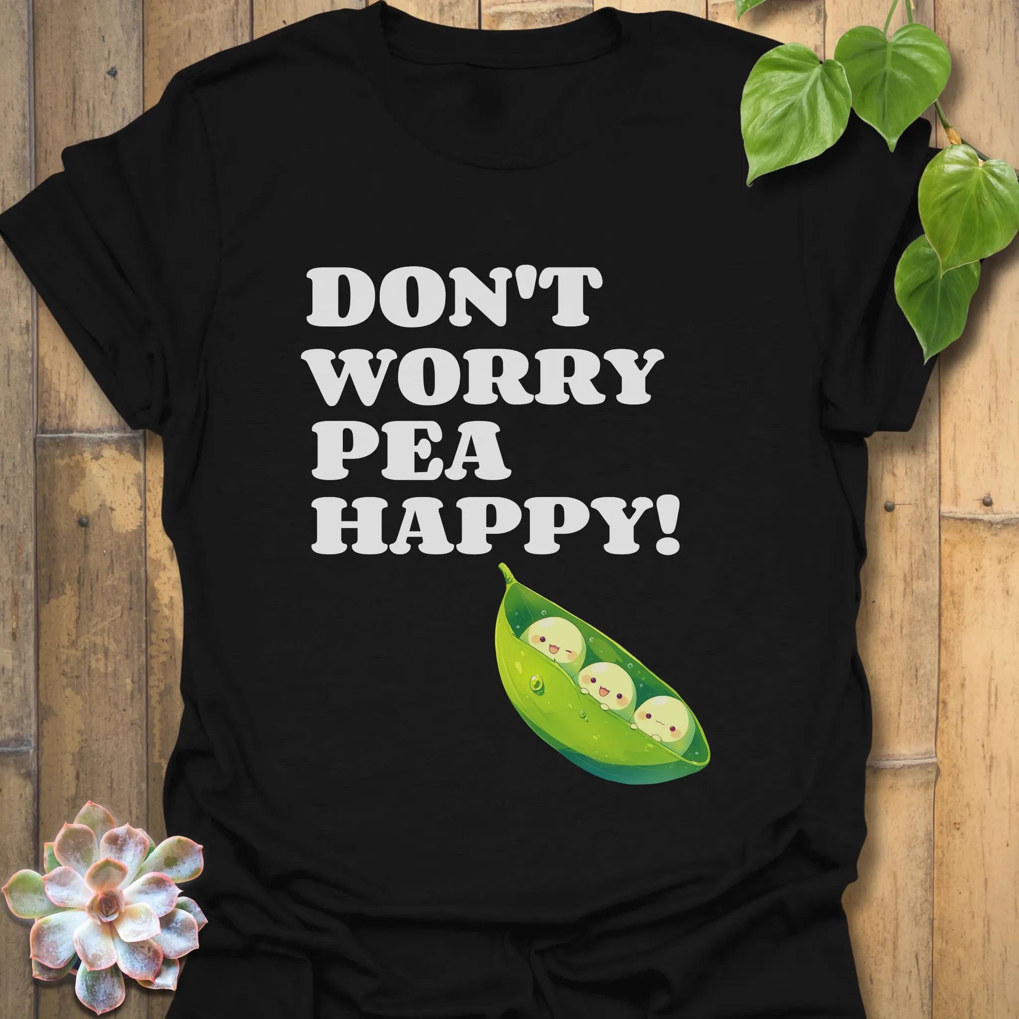 Black t-shirt featuring the design “Don’t Worry Pea Happy” in bold white letters with three smiling peas in a pod illustration