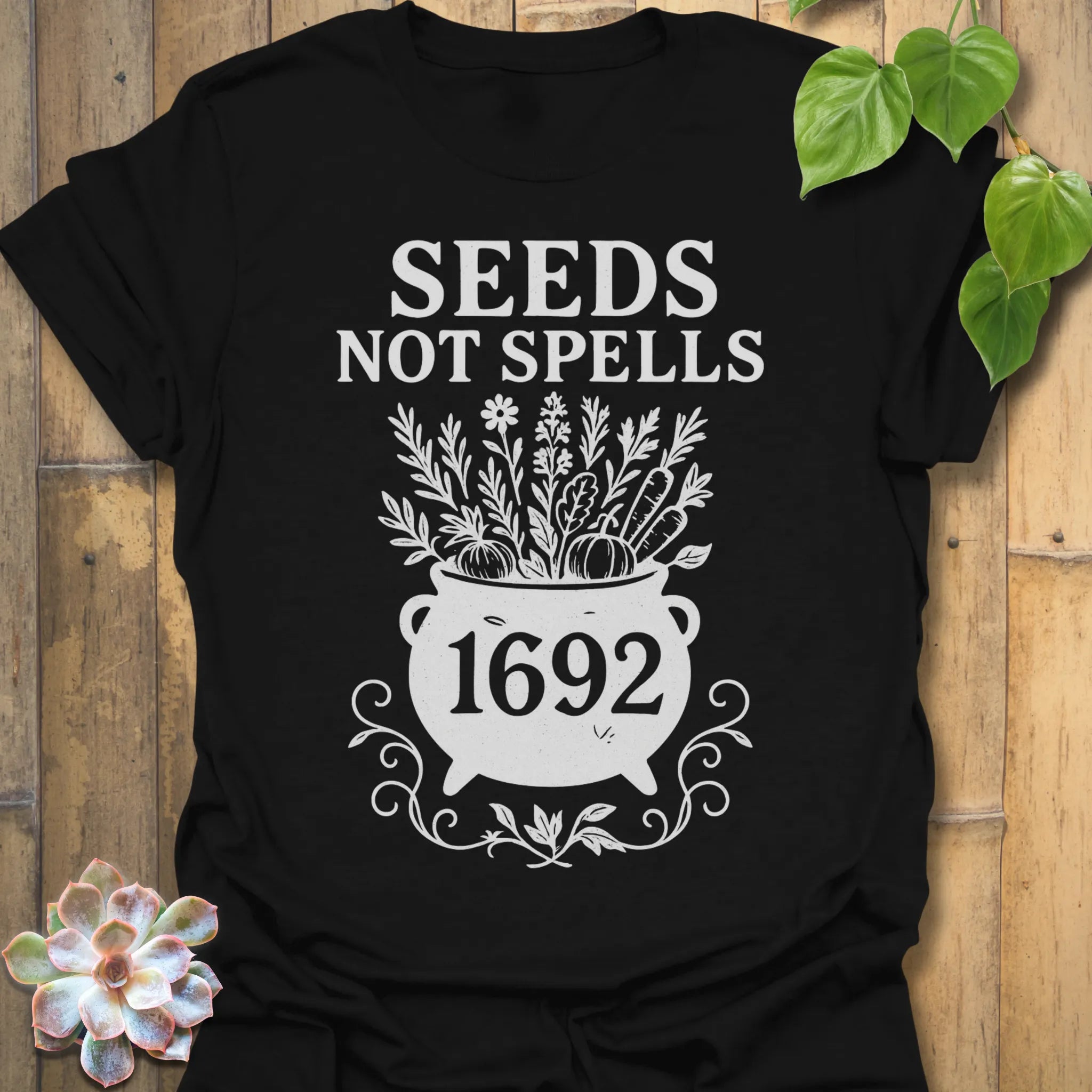Black t-shirt featuring the design Seeds Not Spells printed in bold letters, halloween plant lover shirt.