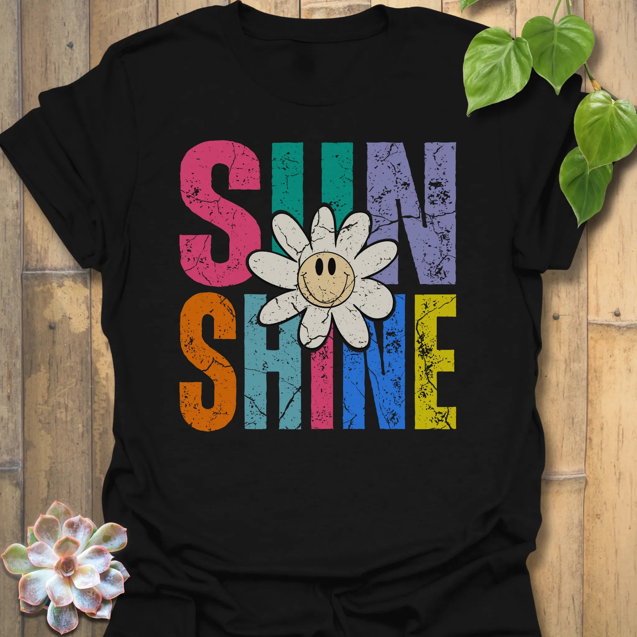 Black t-shirt featuring the design Sunshine printed in bold colorful letters, funny sunflower casual summer shirt.