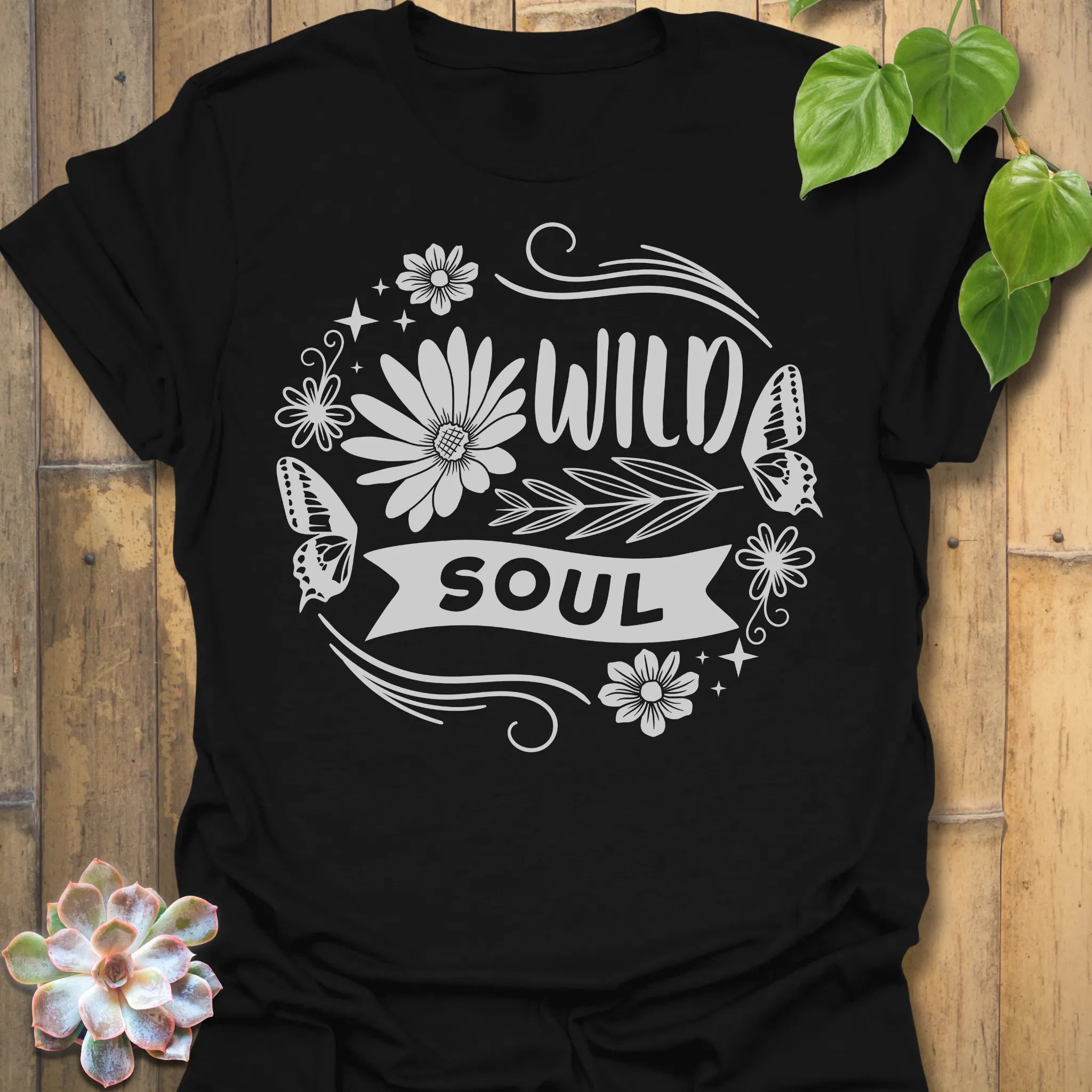 Black t-shirt featuring the design Wild Soul printed in bold black letters, floral graphic tee.
