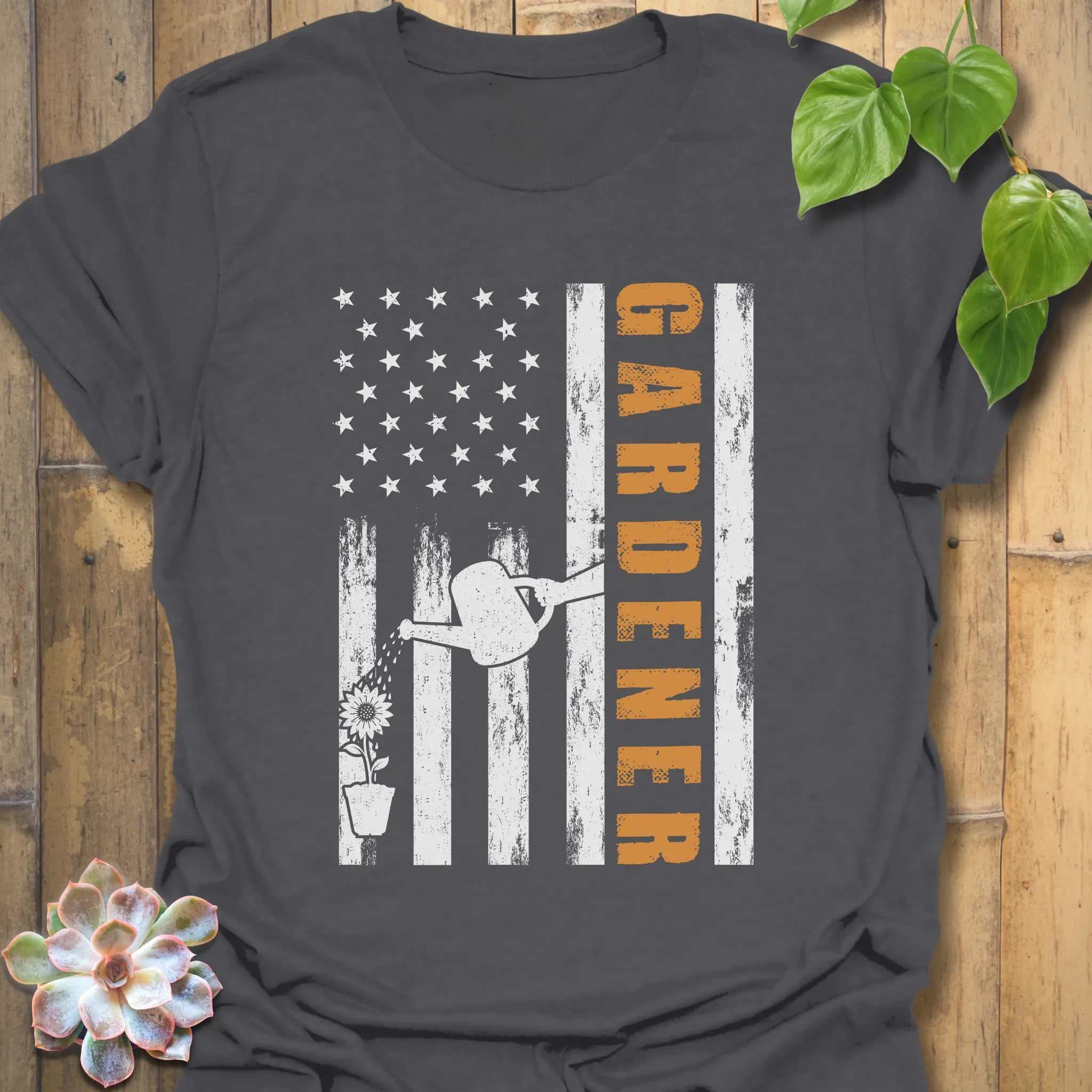Charcoal gardening t-shirt featuring the design Gardener with a vertical word, American flag, plant, and watering sprinkler print, perfect for garden lovers
