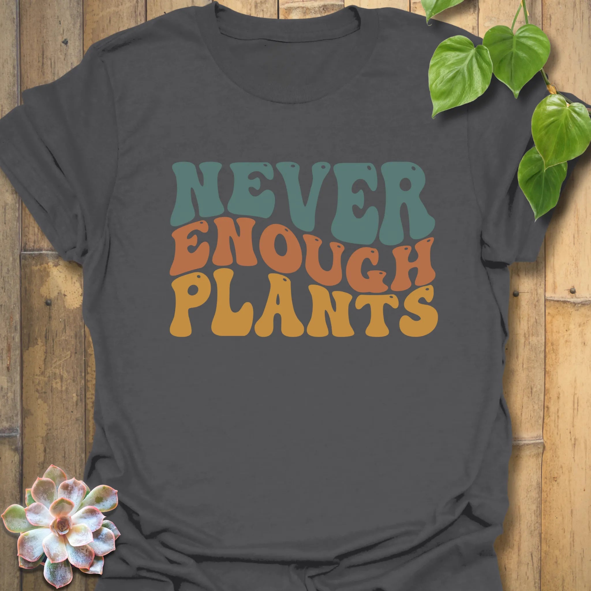 Charcoal grey t-shirt featuring the design Never Enough Plants in bold green text with leaf graphic.