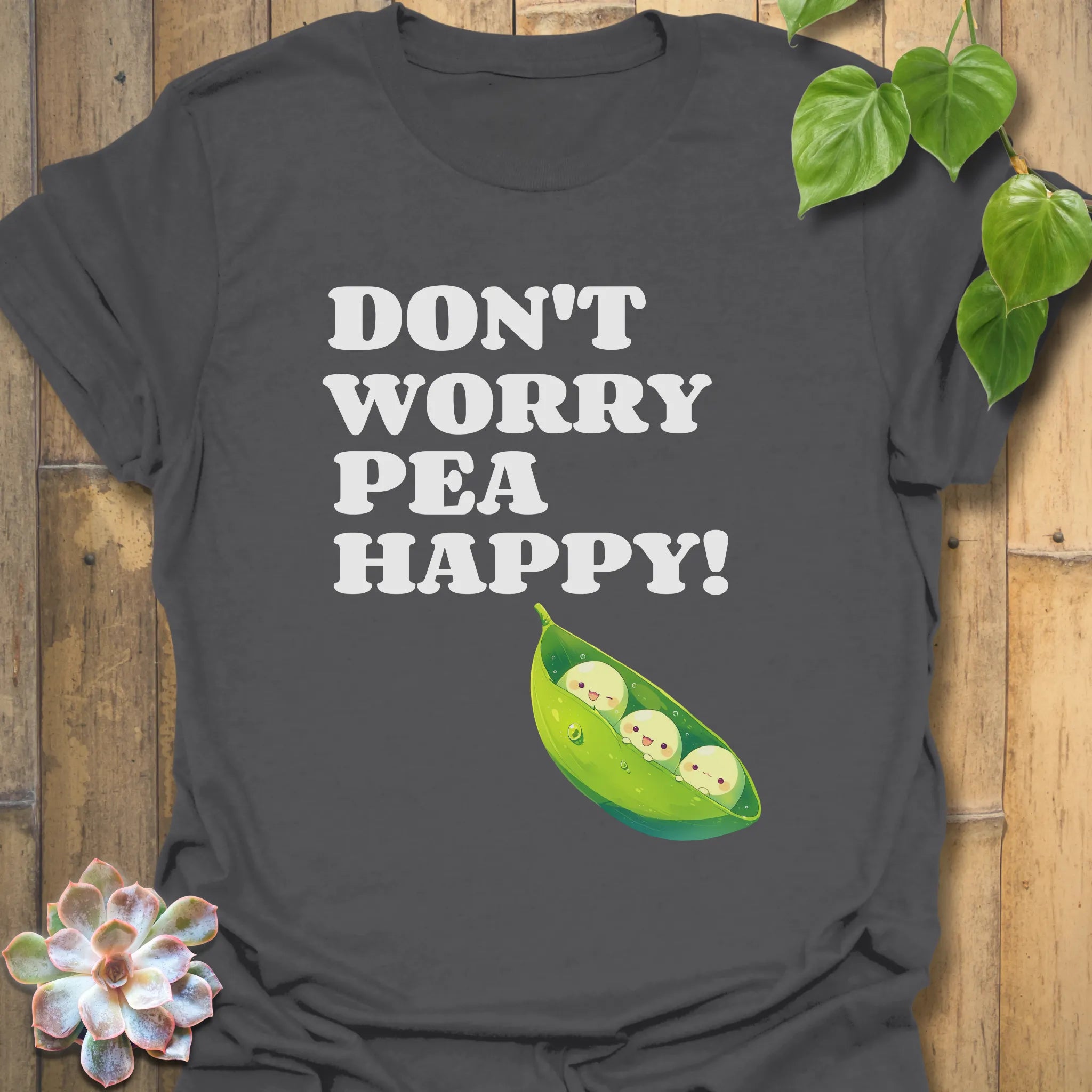 Charcoal t-shirt featuring the design “Don’t Worry Pea Happy” in bold white letters with three smiling peas in a pod illustration