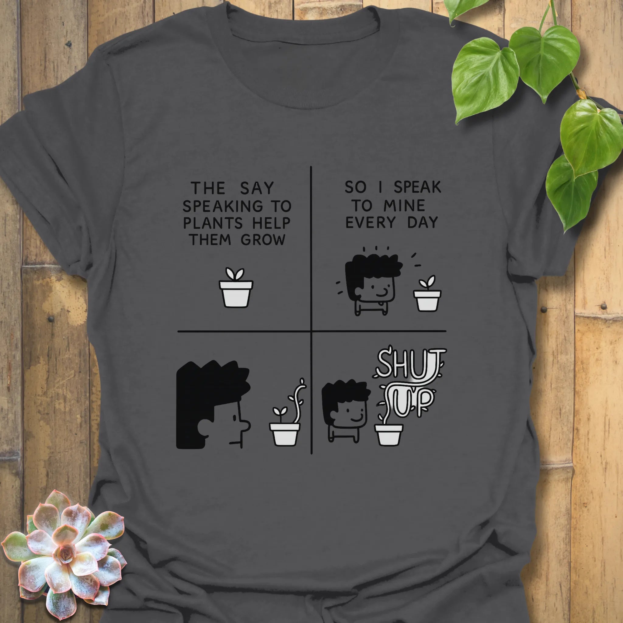 Charcoal t-shirt featuring the design “The say speaking to plants help them grow so I speak to mine everyday” with a funny character of a man and plants printed in bold colours