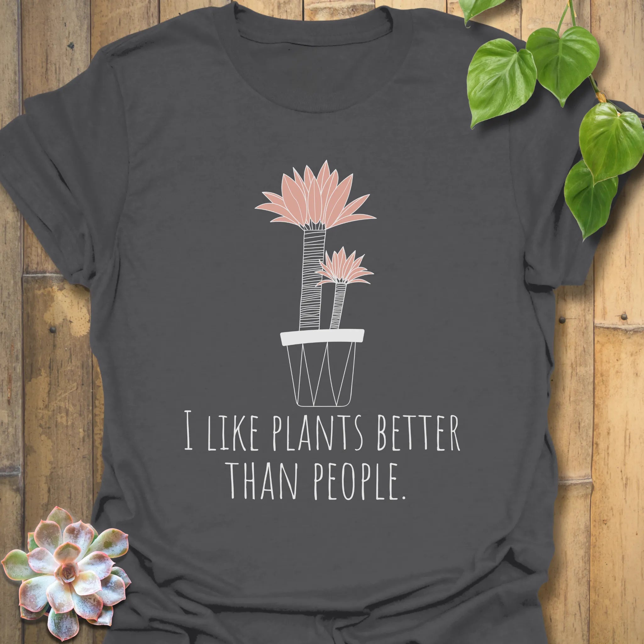 Charcoal t-shirt featuring the text “I like plants better than people” with a flower in a pot design
