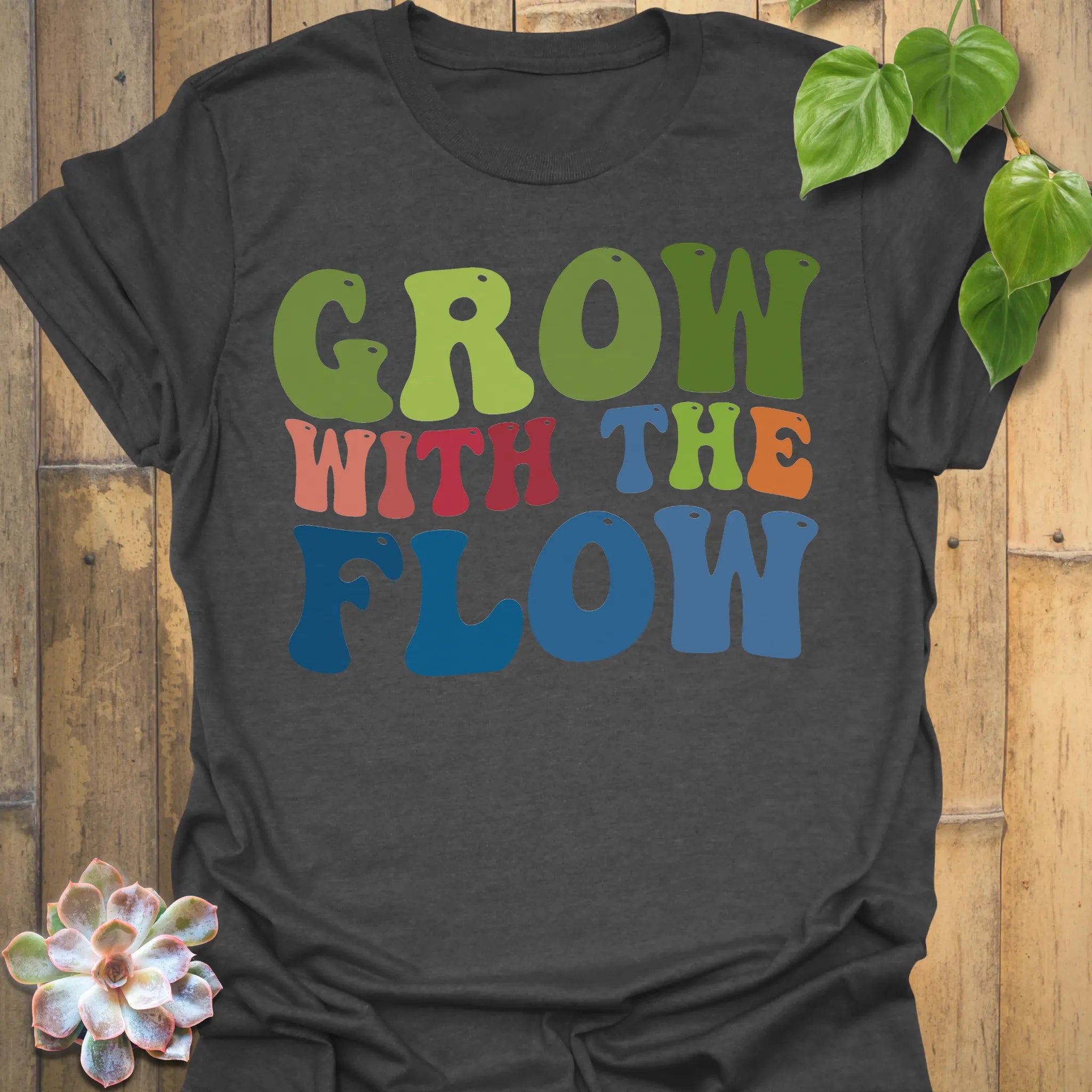 Dark Heather t-shirt featuring the design Grow With The Flow printed in bold colorful letters, mindful garden shirt.