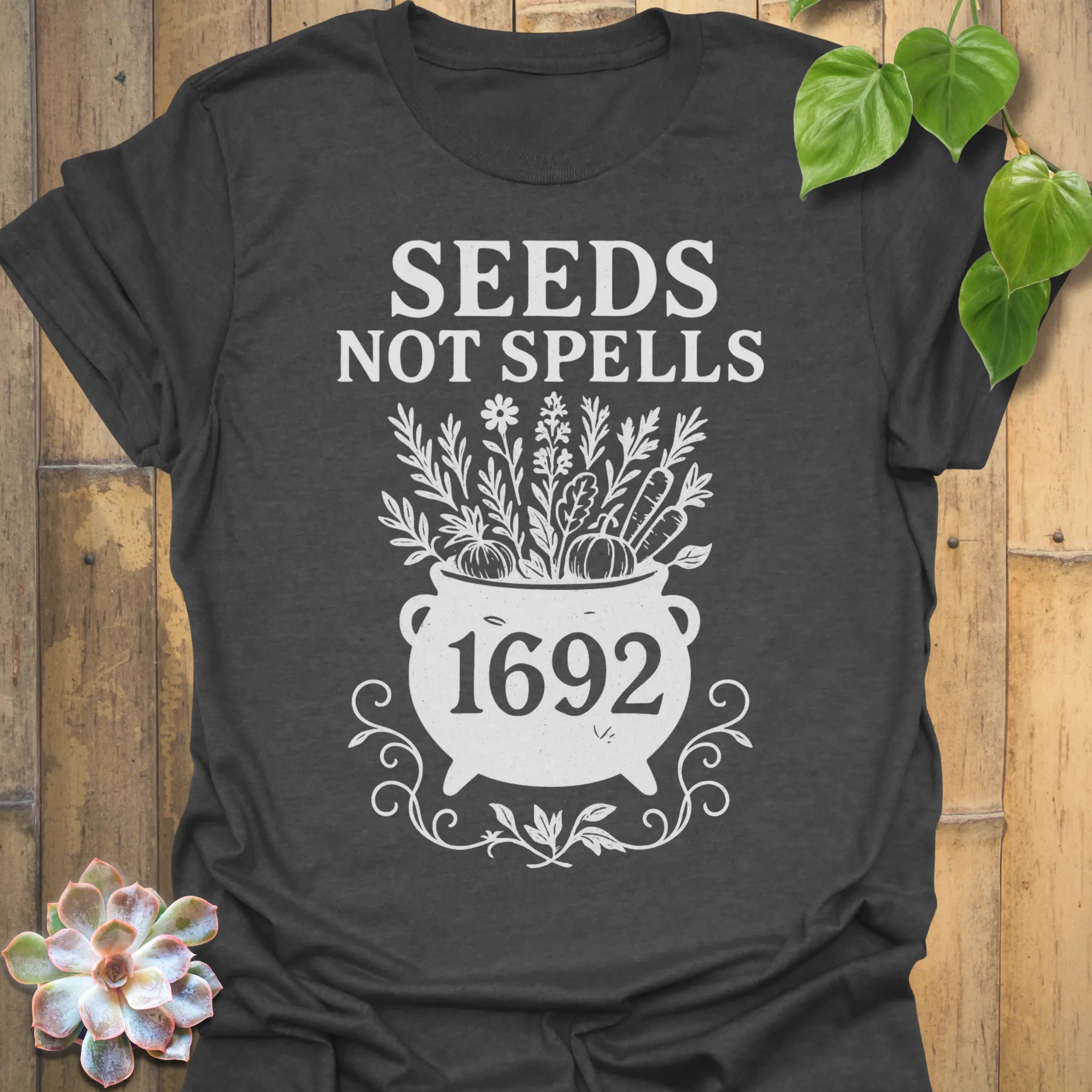 Dark Heather t-shirt featuring the design Seeds Not Spells printed in bold letters, halloween plant lover shirt.