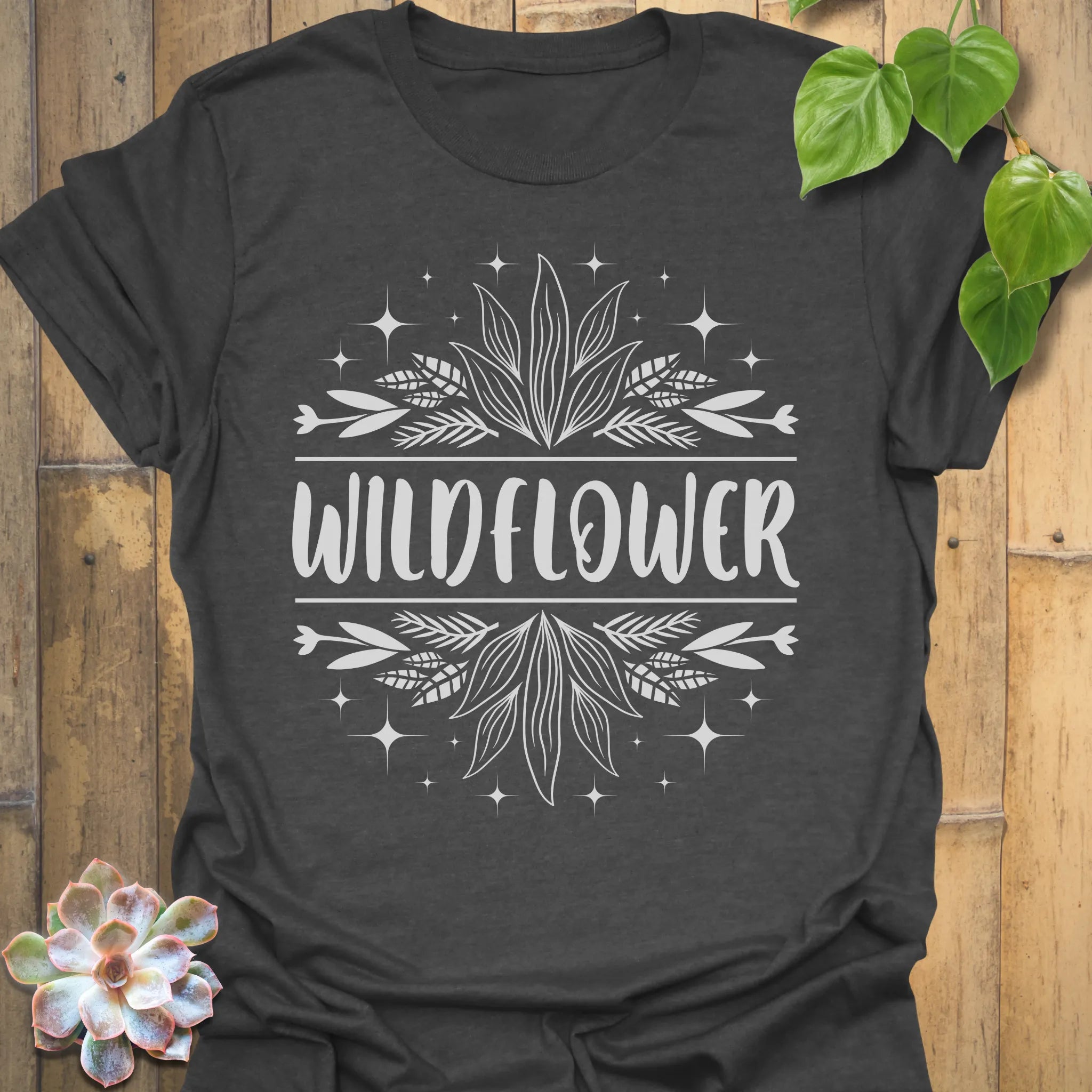 Dark Heather t-shirt featuring the design Wildflower printed in bold white letters, floral graphic shirt.