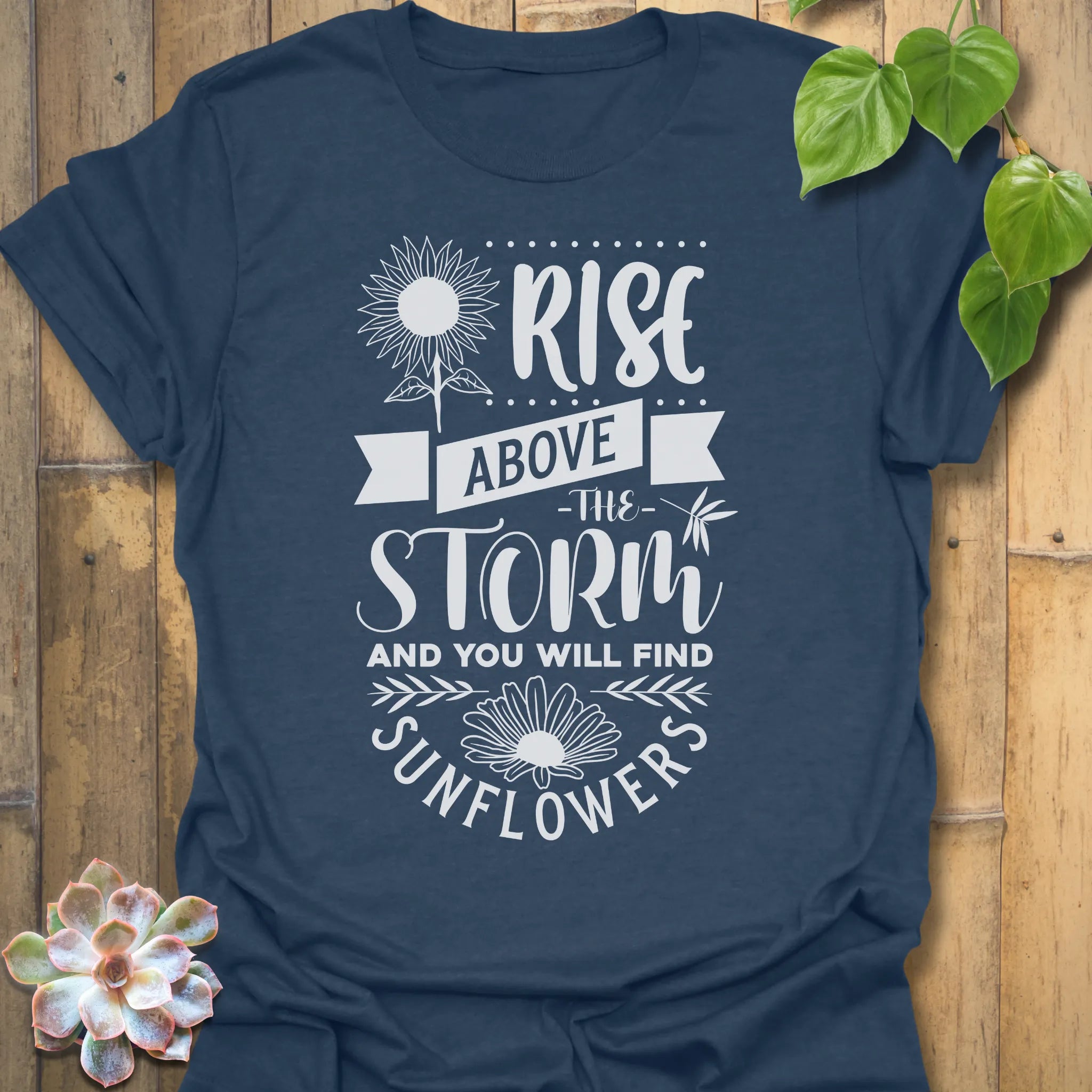 Heather Navy t-shirt featuring the design Above The Storm printed in bold letters, floral inspirational sunflower graphic shirt.