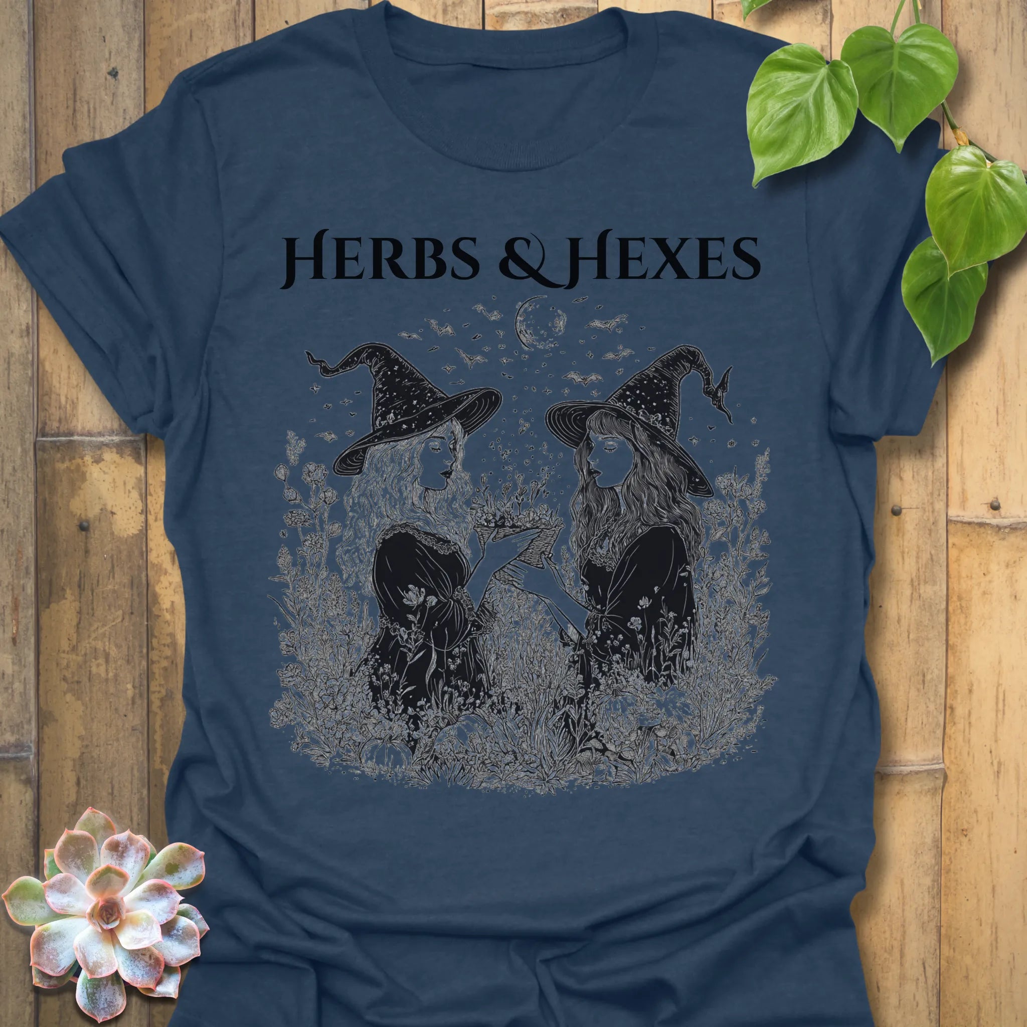 Heather Navy t-shirt featuring the design Herbs & Hexes printed in bold black letters, botanical witch t-shirt.
