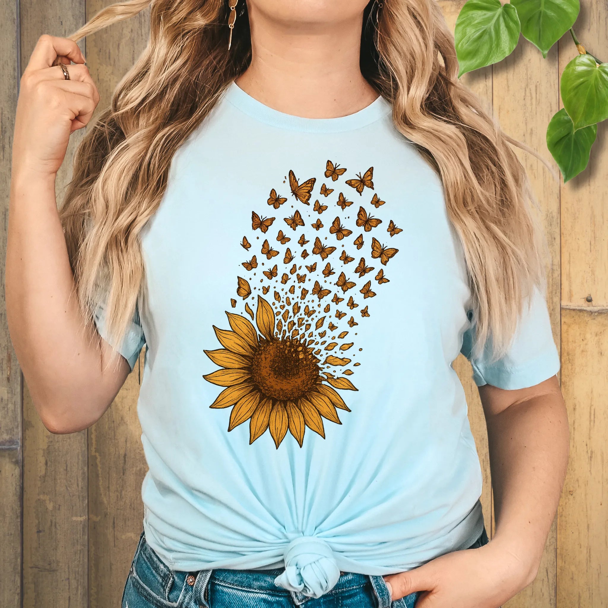A light blue tee featuring a radiant sunflower bursting into butterflies — the perfect mix of strength and serenity for nature lovers.