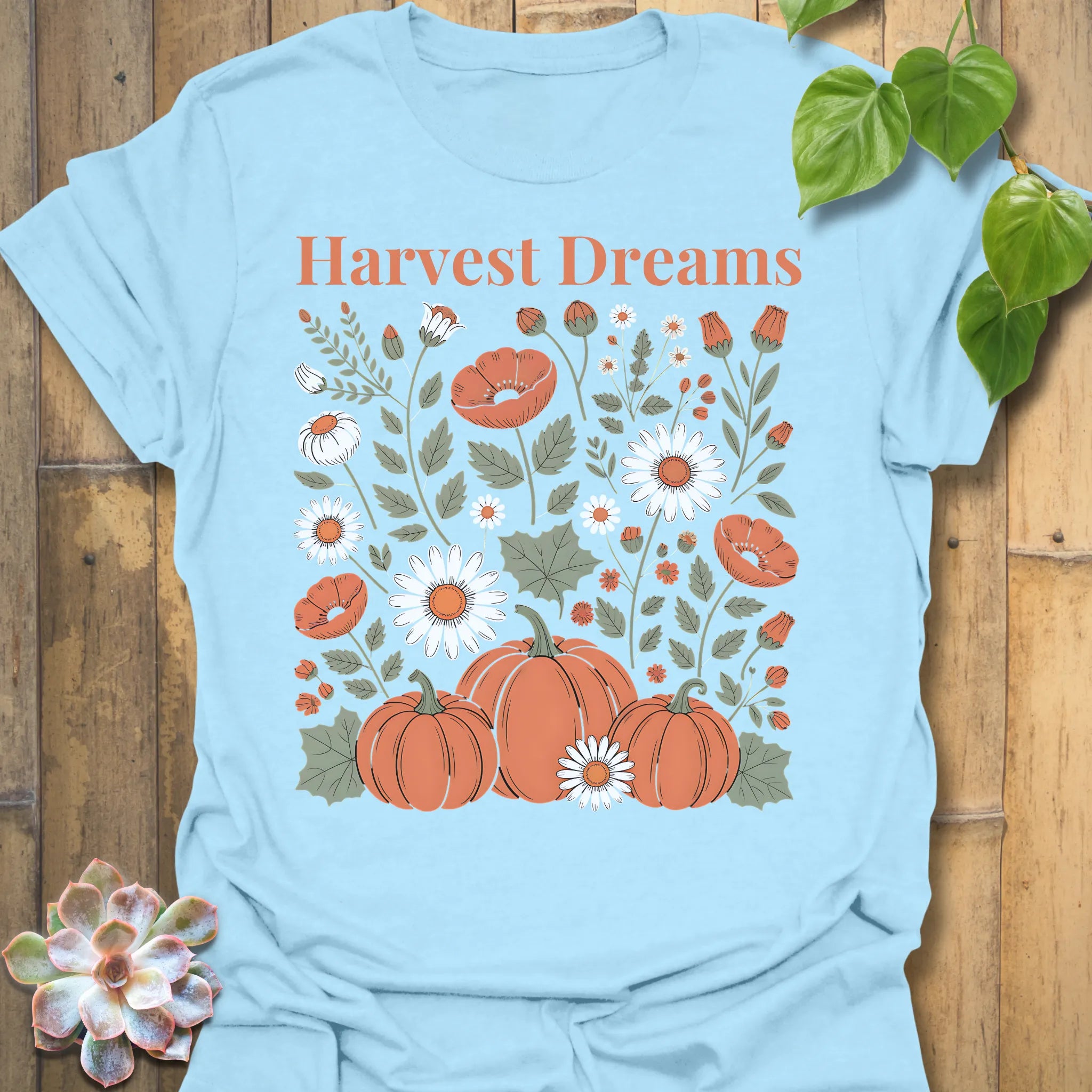 Light Blue t-shirt featuring the design Harvest Dreams printed in bold orange letters, cosy harvest tee.
