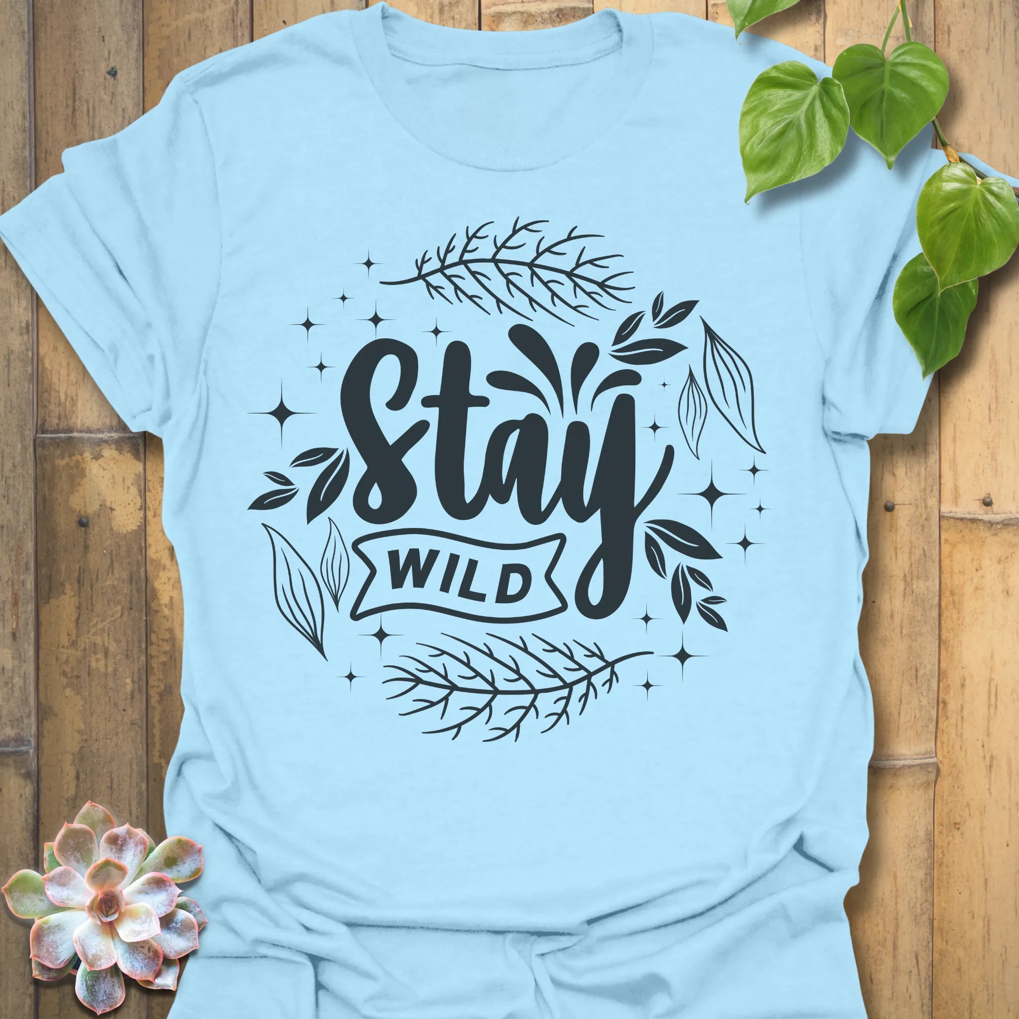 Light Blue t-shirt featuring the design Stay Wild printed in bold white letters, floral graphic lover shirt.
