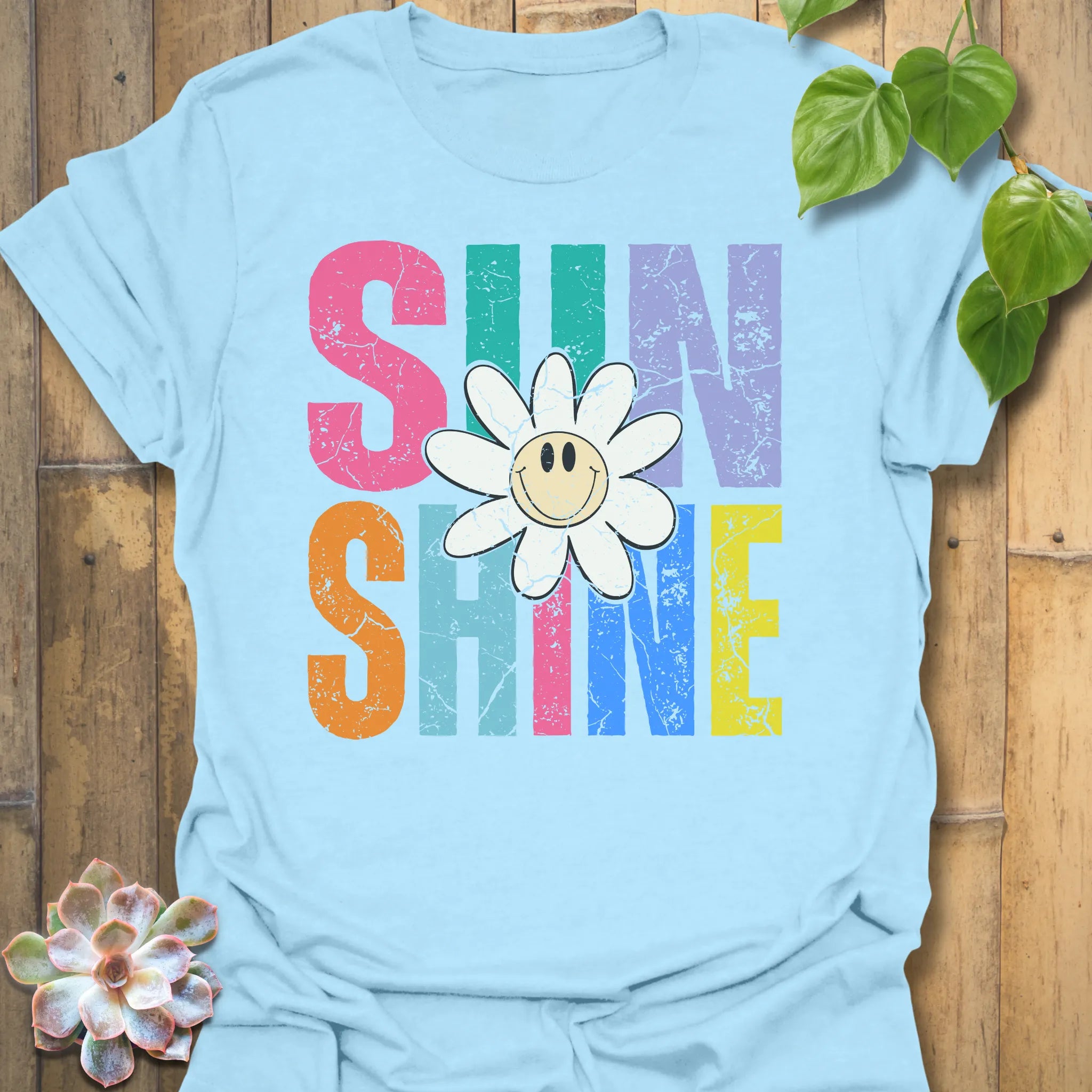 Light Blue t-shirt featuring the design Sunshine printed in bold colorful letters, funny sunflower casual summer shirt.