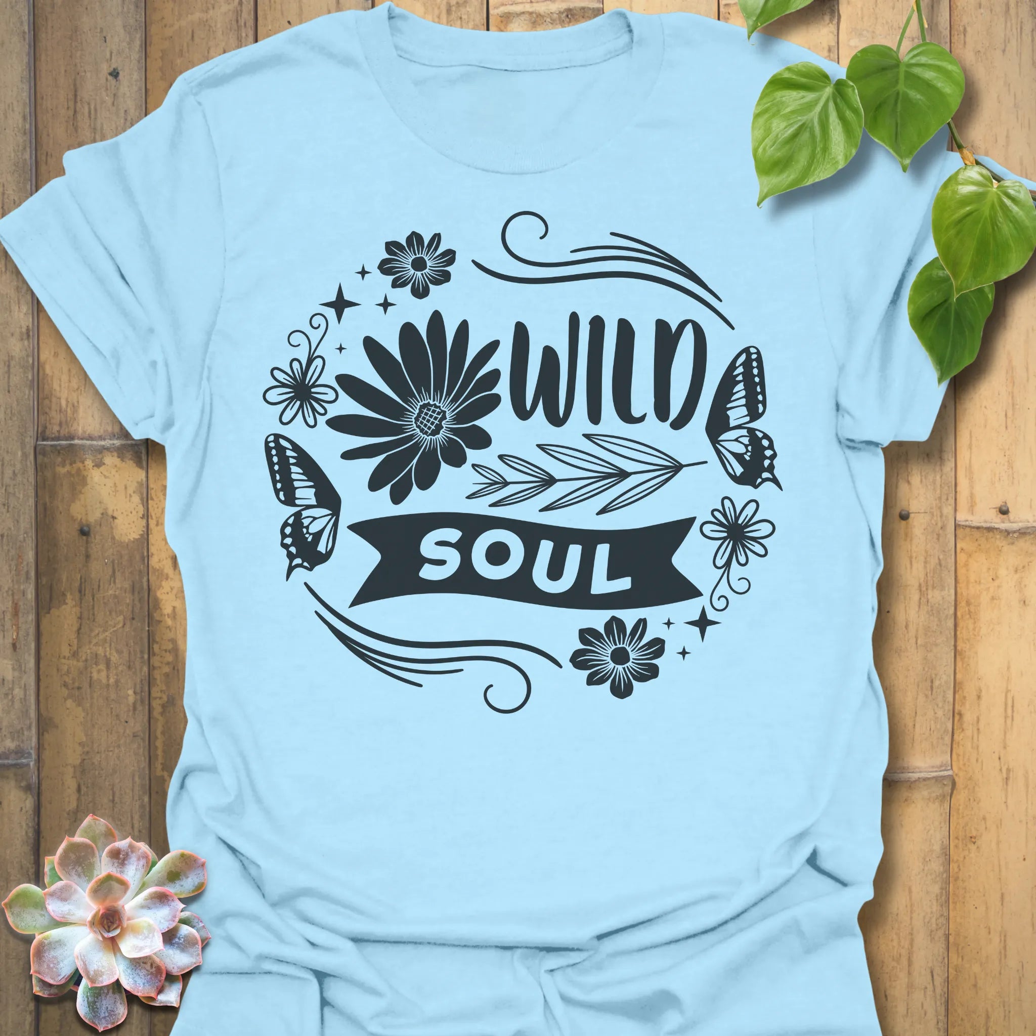 Light Blue t-shirt featuring the design Wild Soul printed in bold black letters, floral graphic tee.