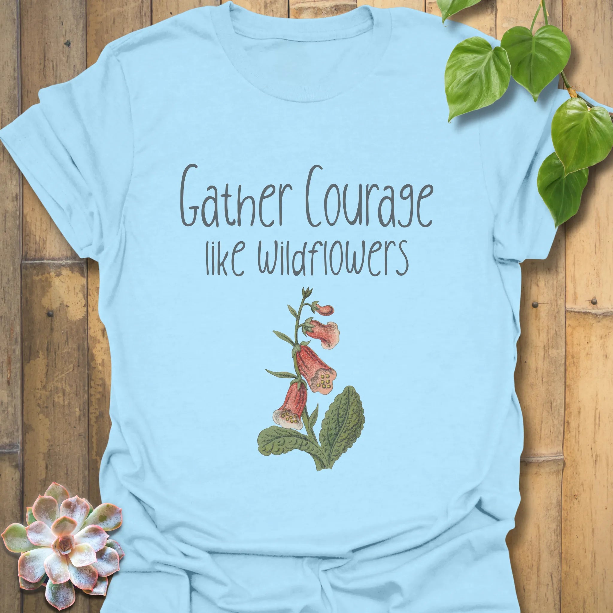 Light blue floral inspirational t-shirt with the words ‘Gather courage like wildflowers’ printed alongside a delicate flower design