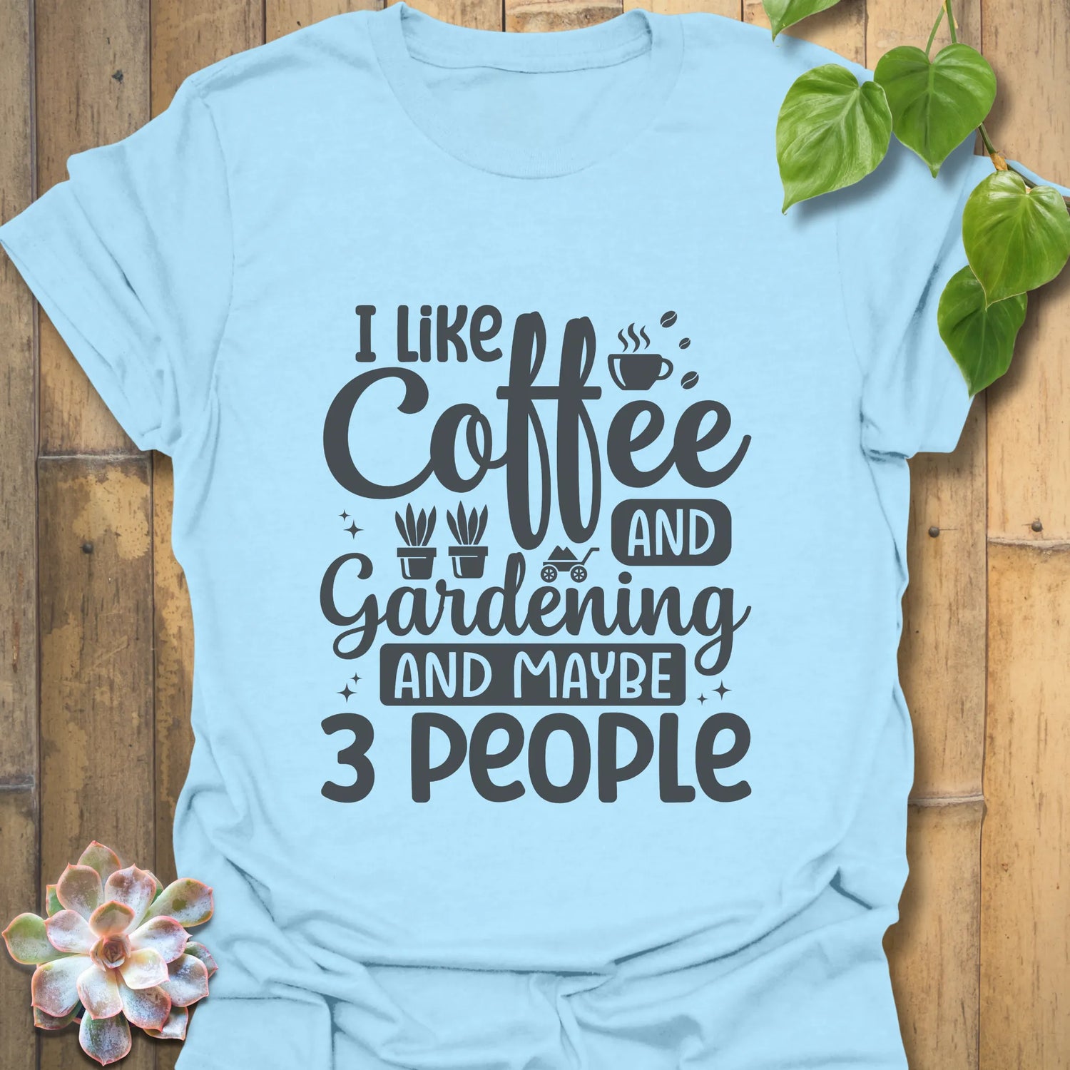 Light blue t-shirt featuring the design "I like coffee and gardening and maybe 3 people" fun coffee lover shirt.