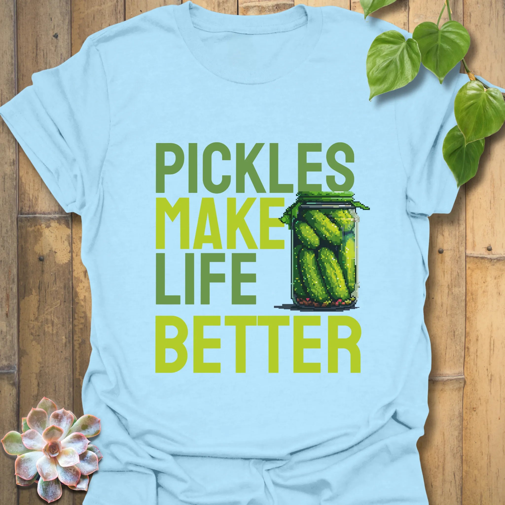 Light blue t-shirt featuring the design “Pickles make life better” with cucumbers inside a glass jar