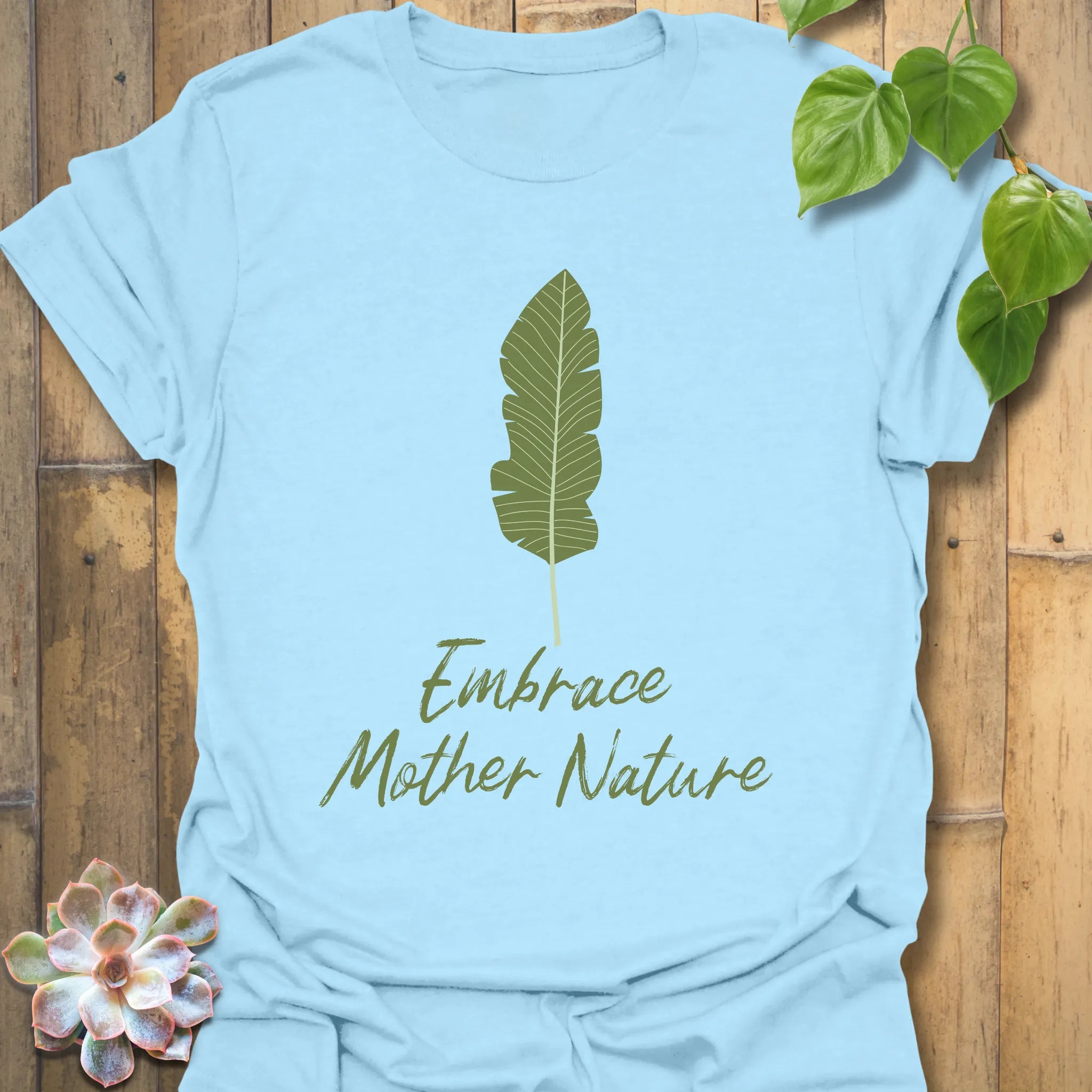 Light blue t-shirt featuring the text “Embrace Mother Nature” alongside a green leaf print