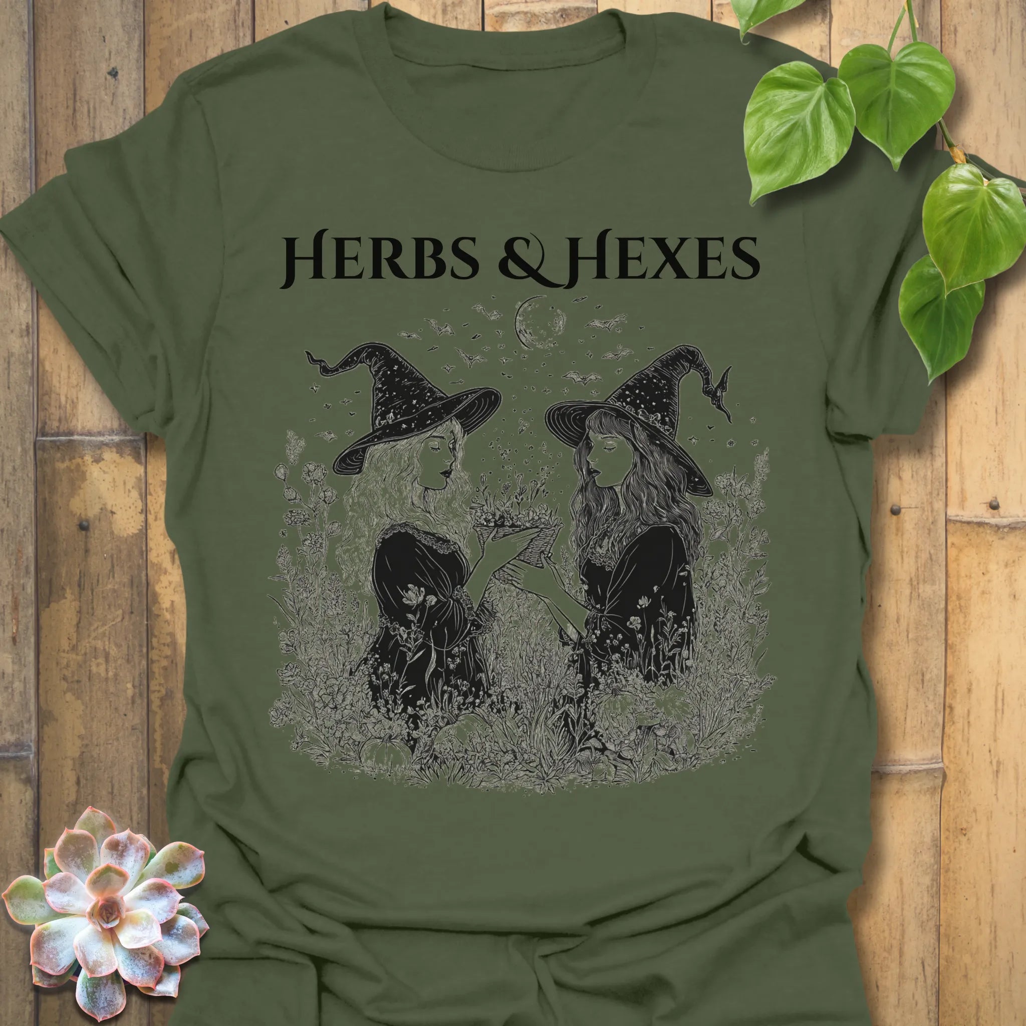 Military Green t-shirt featuring the design Herbs & Hexes printed in bold black letters, botanical witch t-shirt.