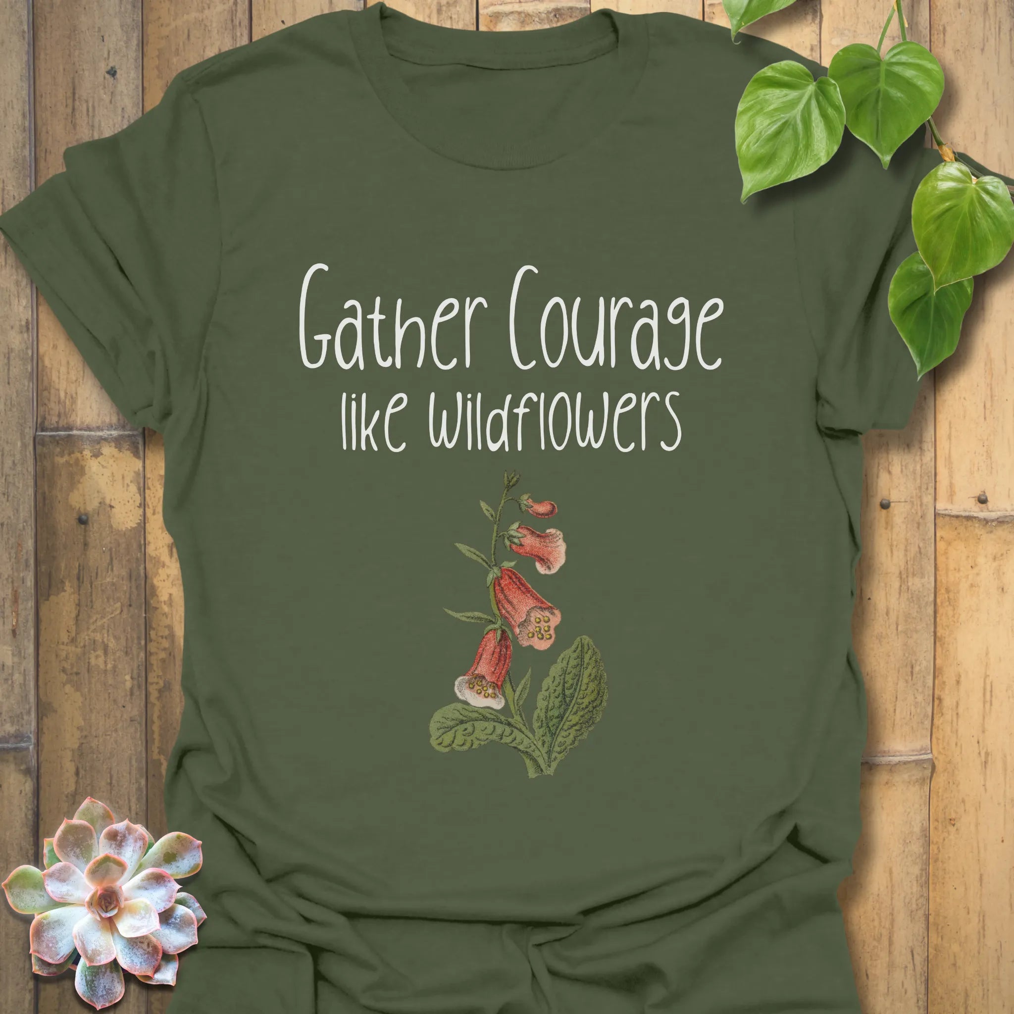 Military green botanical graphic t-shirt displaying the quote ‘Gather courage like wildflowers’ with a natural flower print