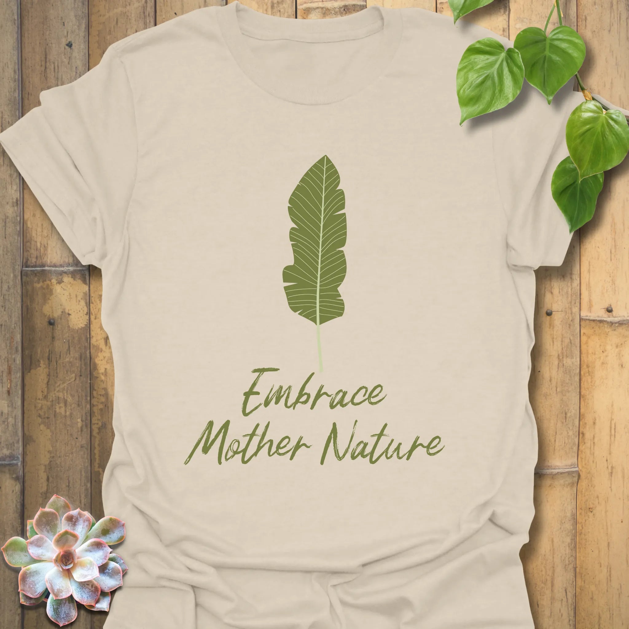 Natural colour t-shirt displaying the text “Embrace Mother Nature” with a leaf-inspired print