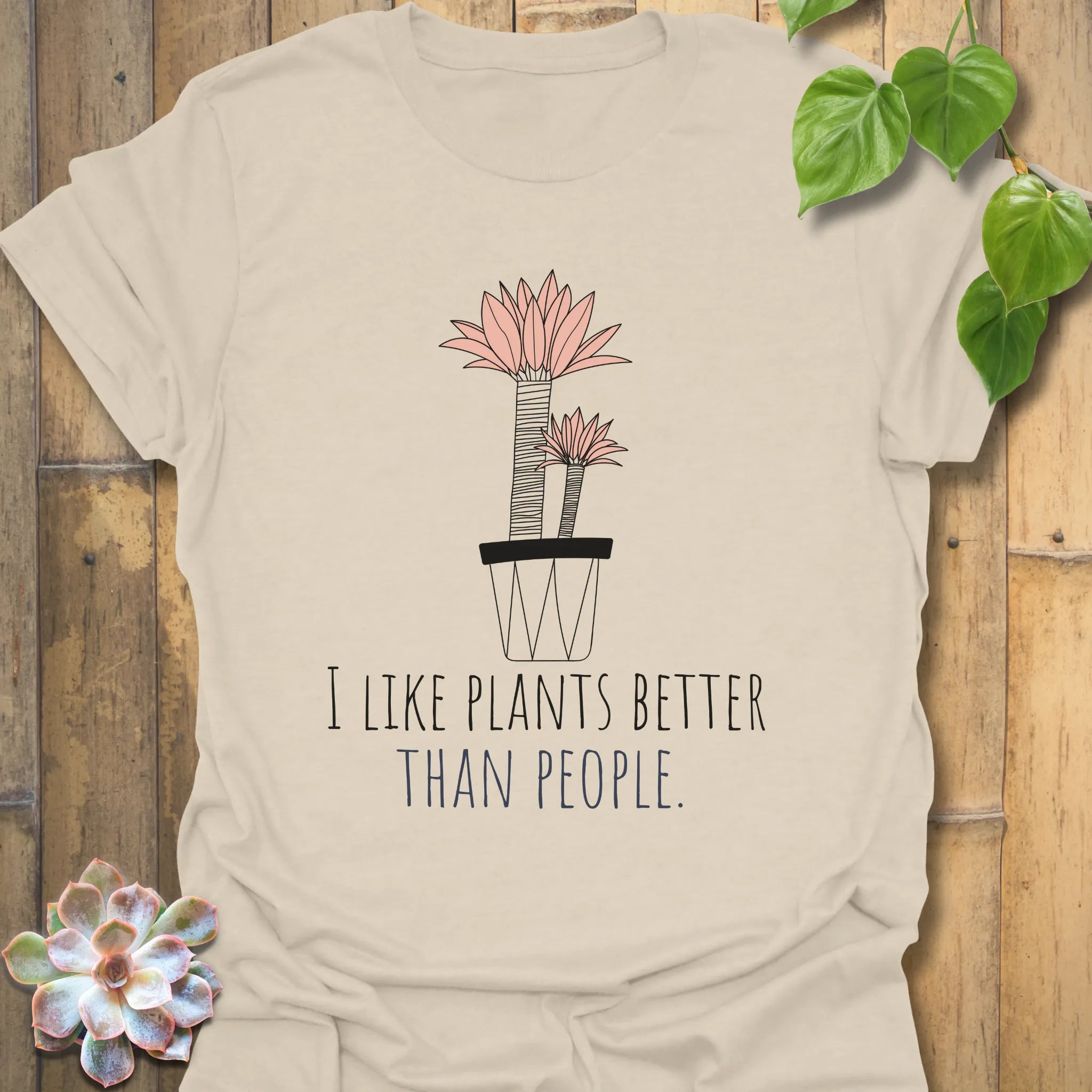 Natural colour t-shirt with the phrase “I like plants better than people” and a flower in a pot design
