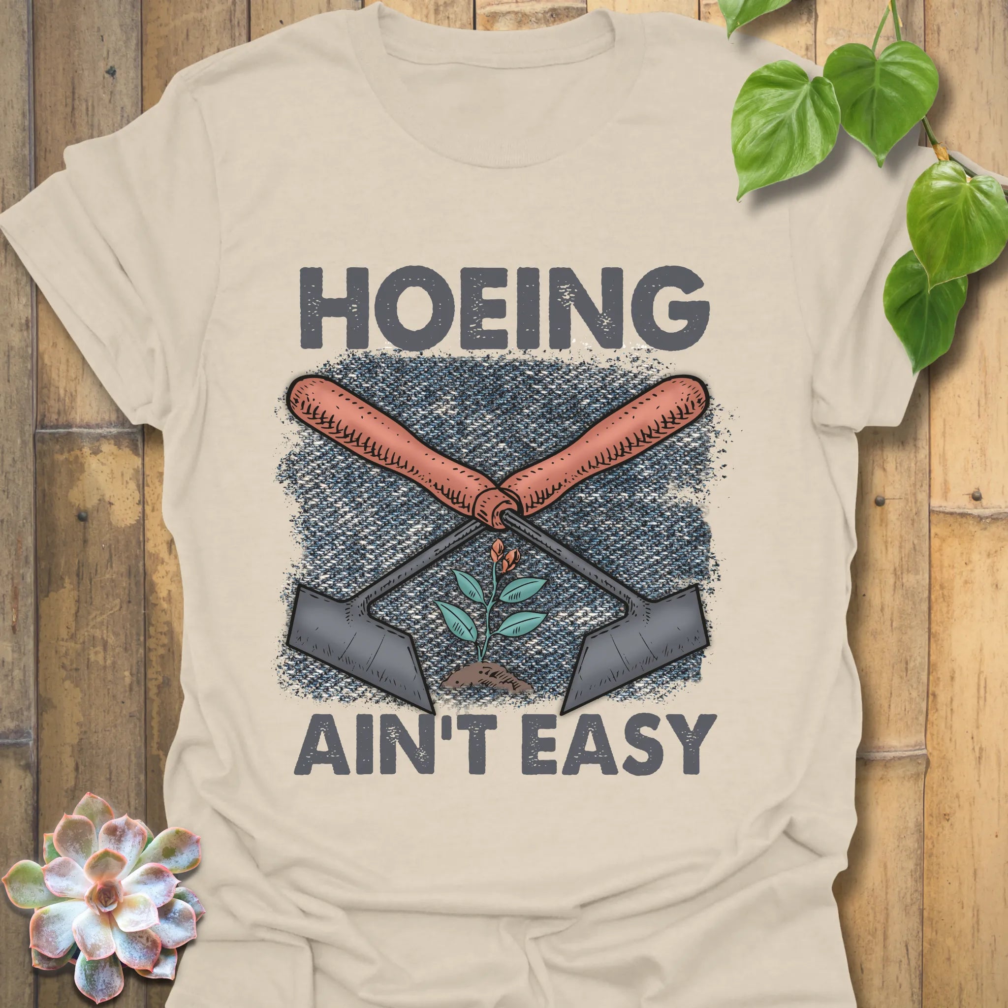Natural t-shirt featuring the design Hoeing Ain’t Easy, rustic garden graphic tee.