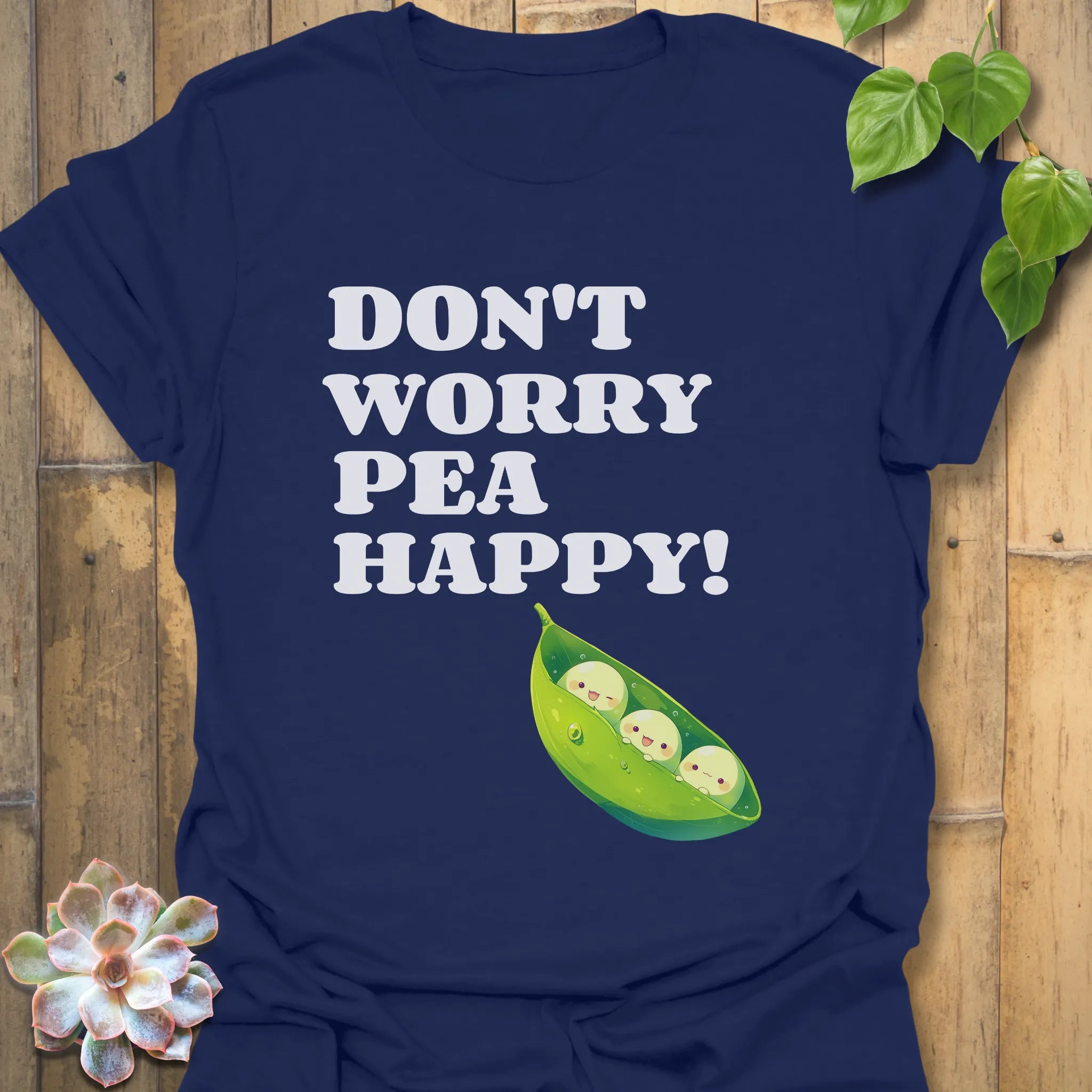 Navy t-shirt featuring the design “Don’t Worry Pea Happy” in bold white letters with three smiling peas in a pod illustration