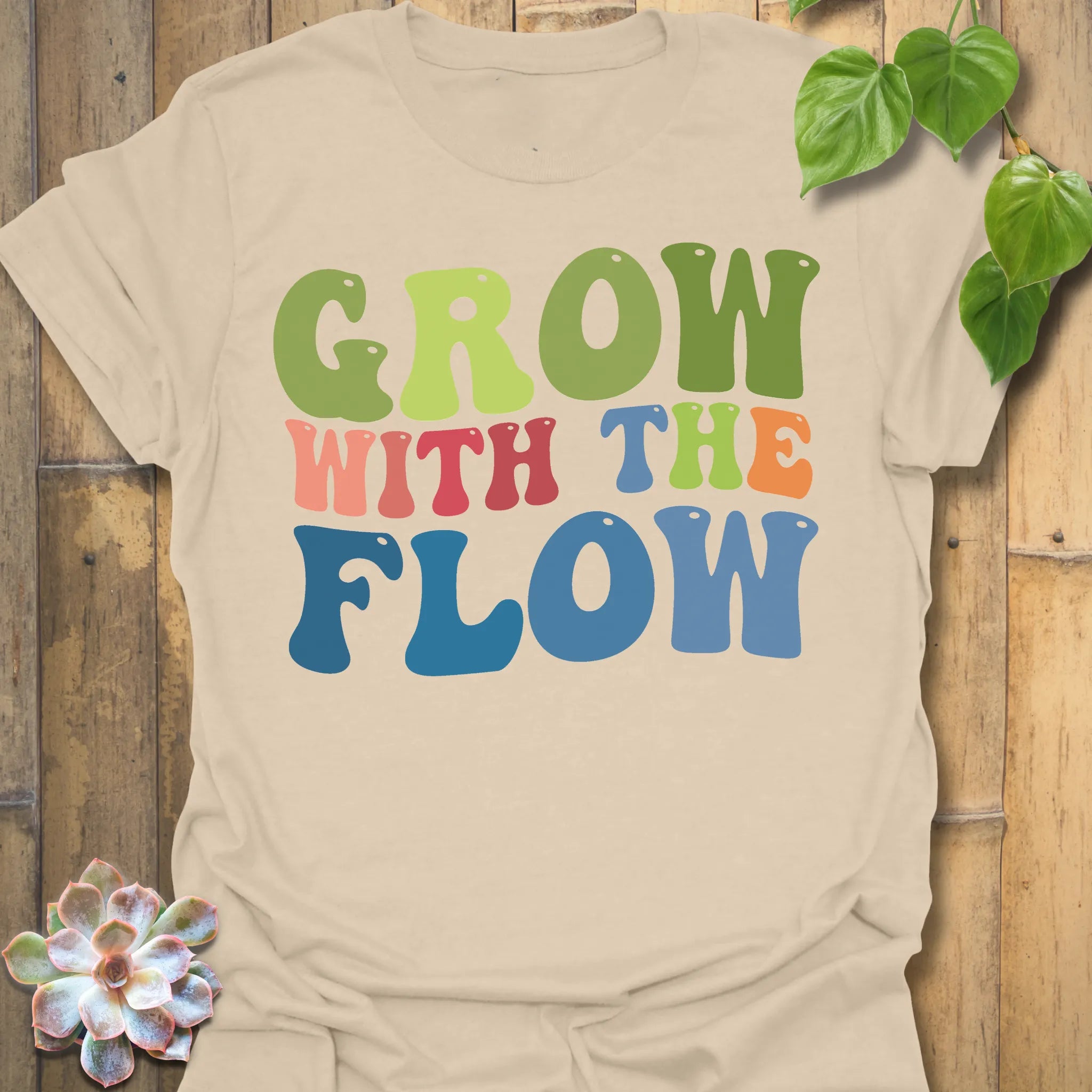 Sand t-shirt featuring the design Grow With The Flow printed in bold colorful letters, mindful garden shirt.