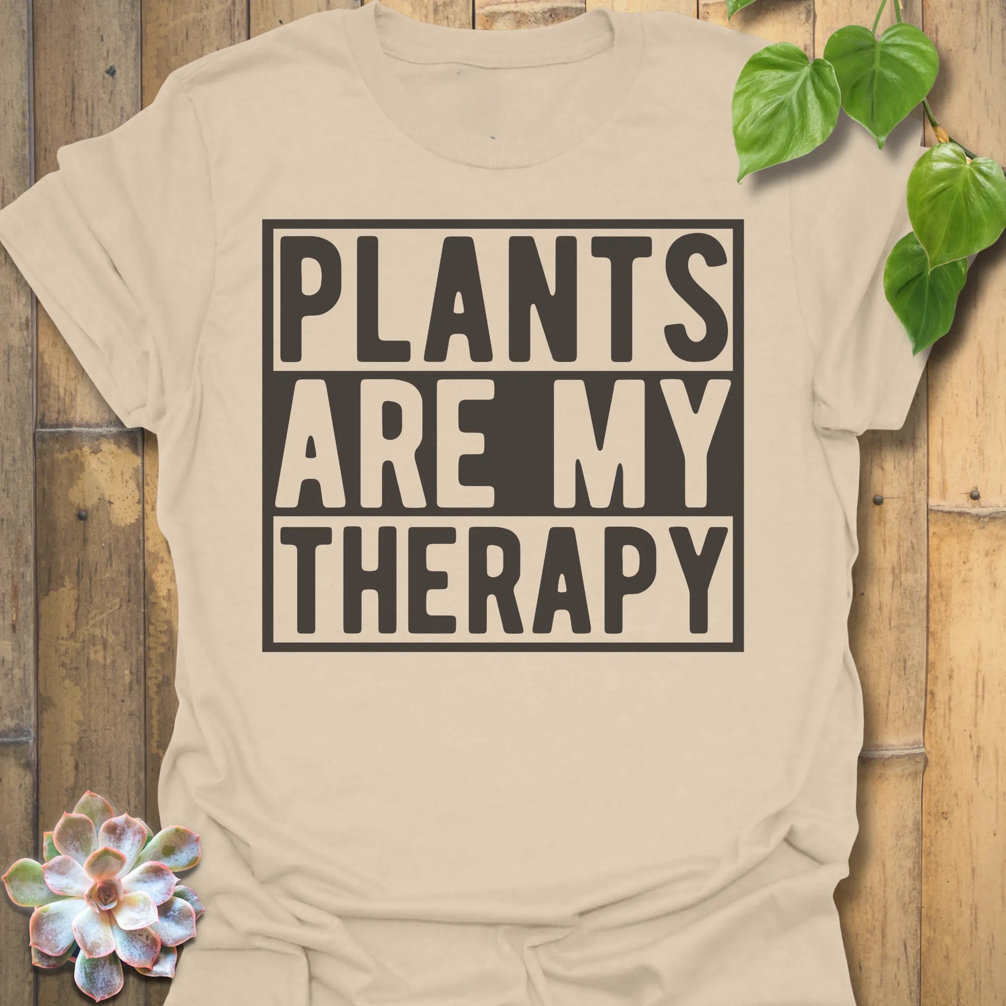 Sand t-shirt featuring the design Plants Are My Therapy printed in bold letters, plant lover shirt.