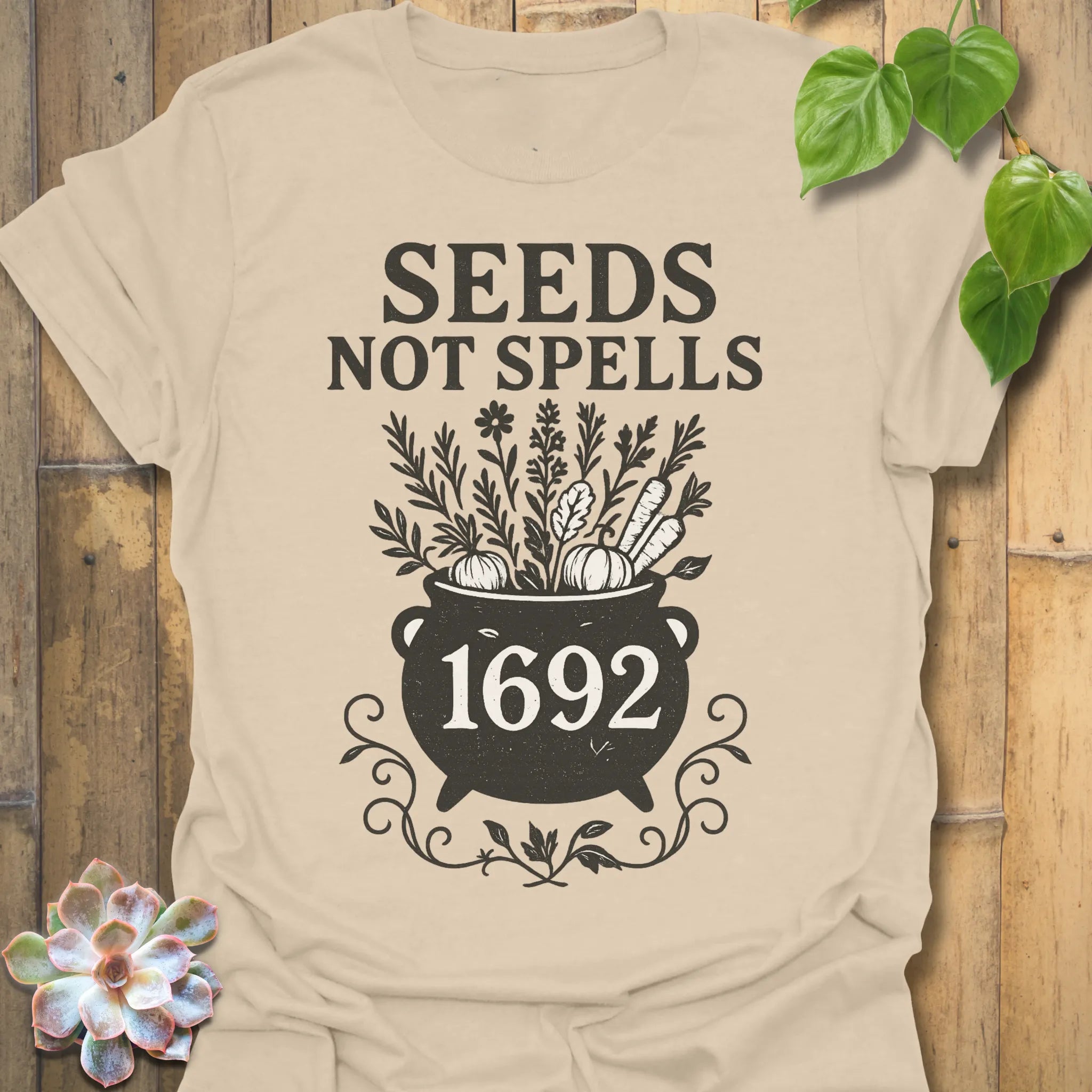 Sand t-shirt featuring the design Seeds Not Spells printed in bold letters, halloween plant lover shirt.