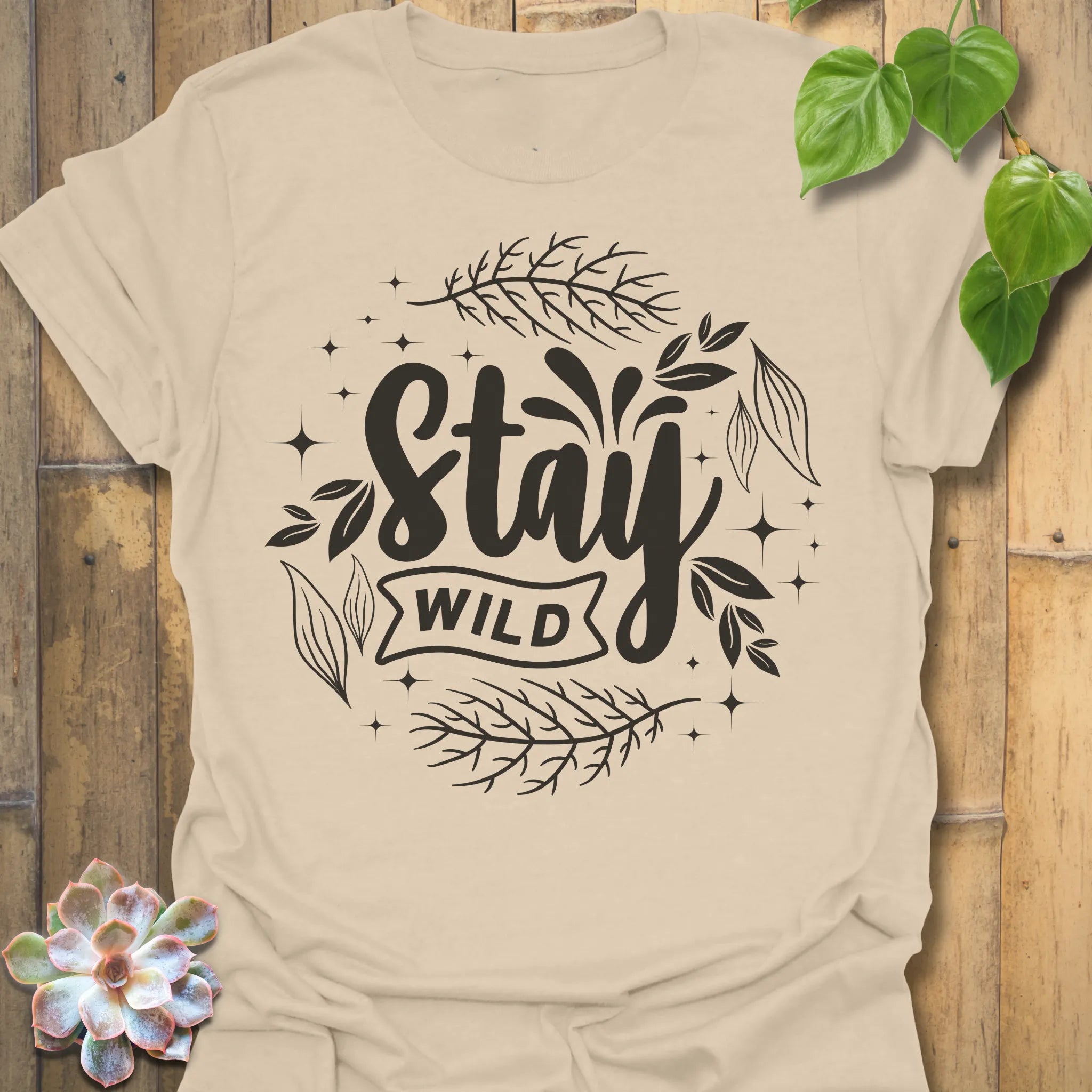 Sand t-shirt featuring the design Stay Wild printed in bold white letters, floral graphic lover shirt.