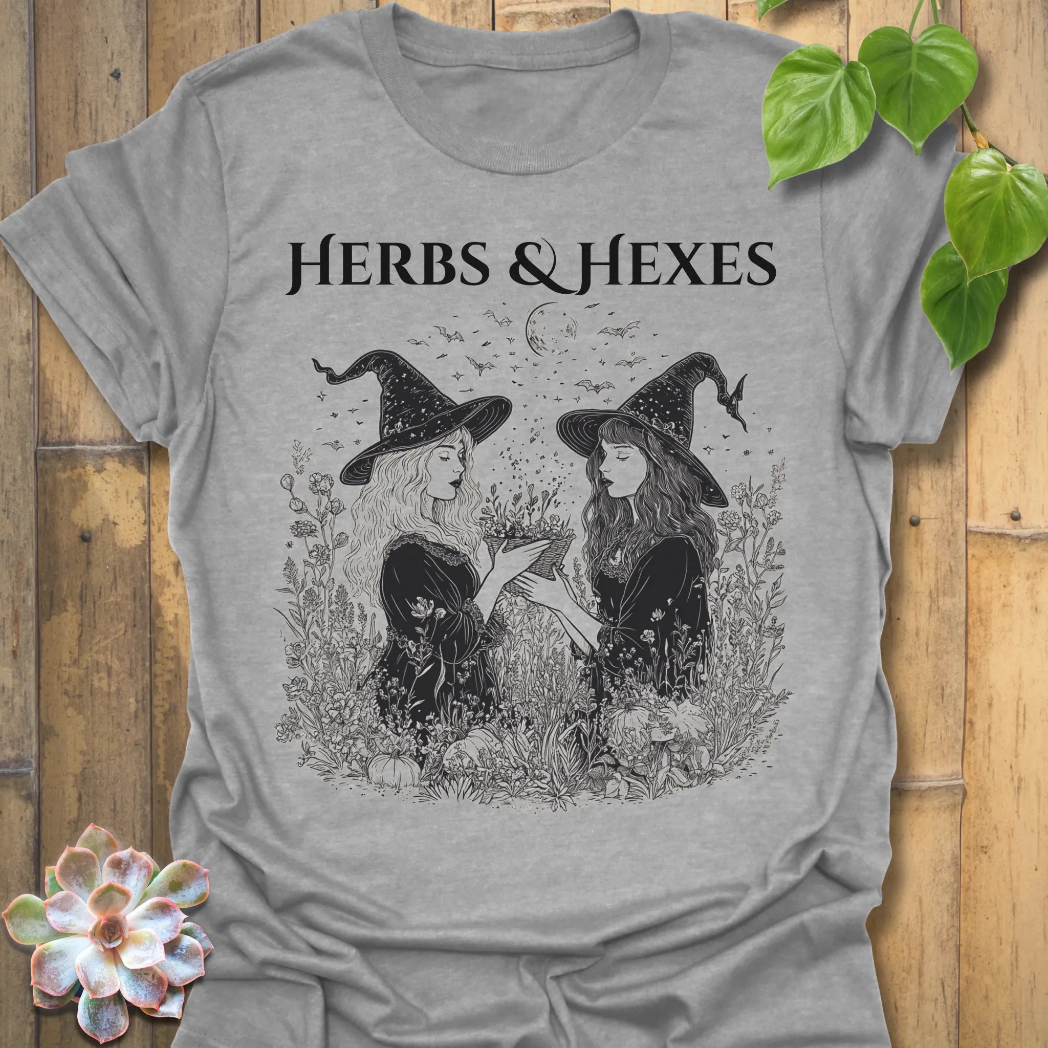 Sport Grey t-shirt featuring the design Herbs & Hexes printed in bold black letters, botanical witch t-shirt.