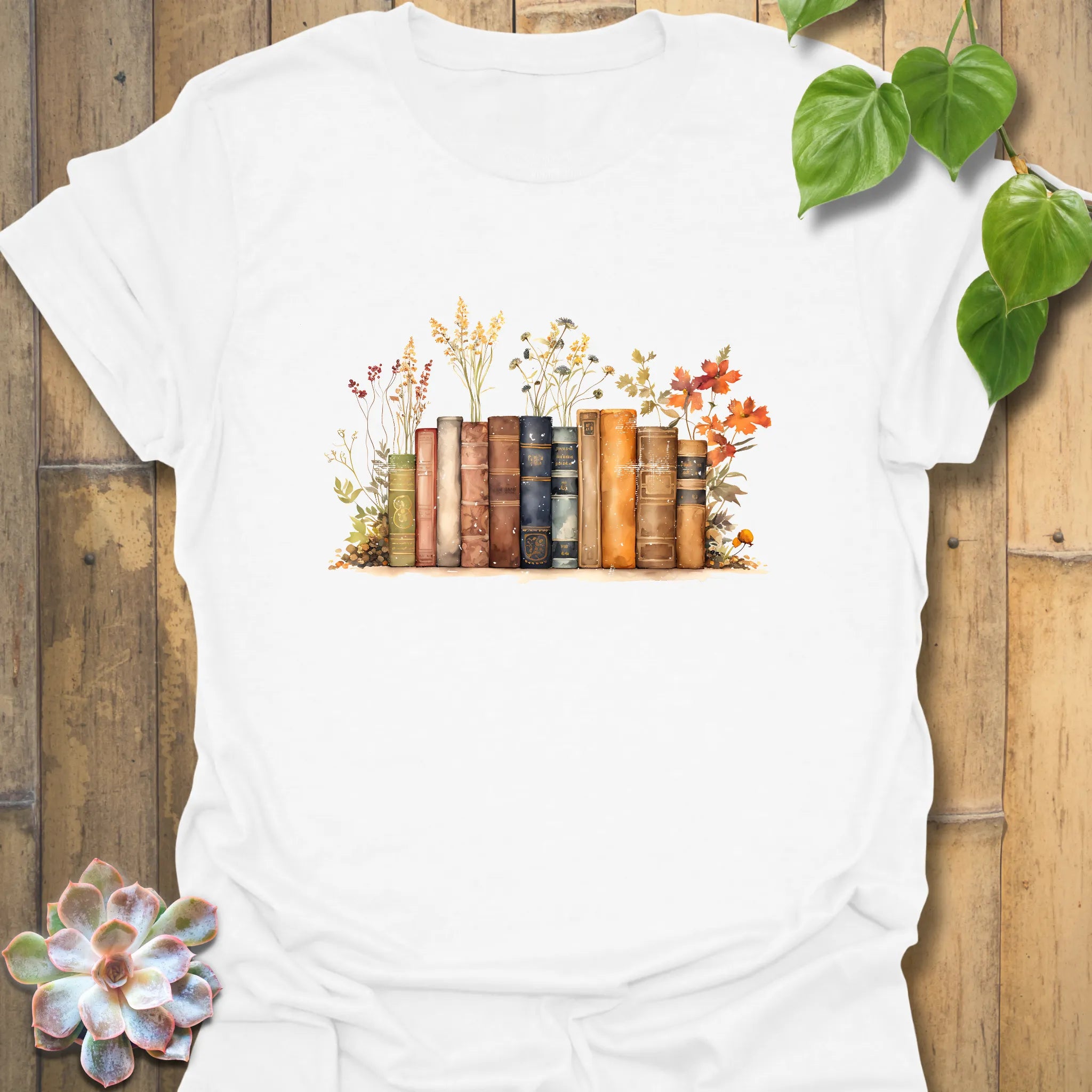 White “Wildflower Library” T-shirt with a beautifully illustrated vintage book stack and wildflowers — crisp, classic, and bookish.