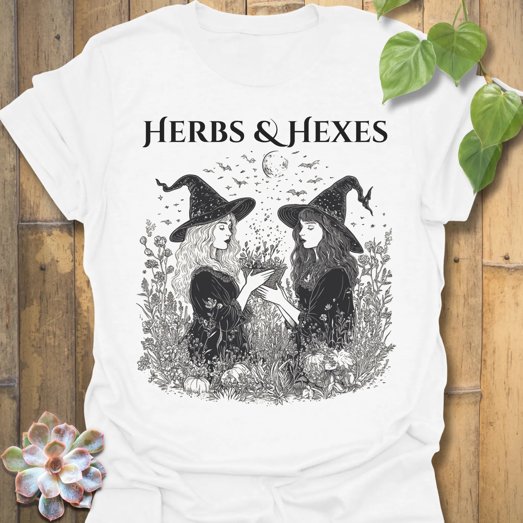 White t-shirt featuring the design Herbs & Hexes printed in bold black letters, botanical witch t-shirt.