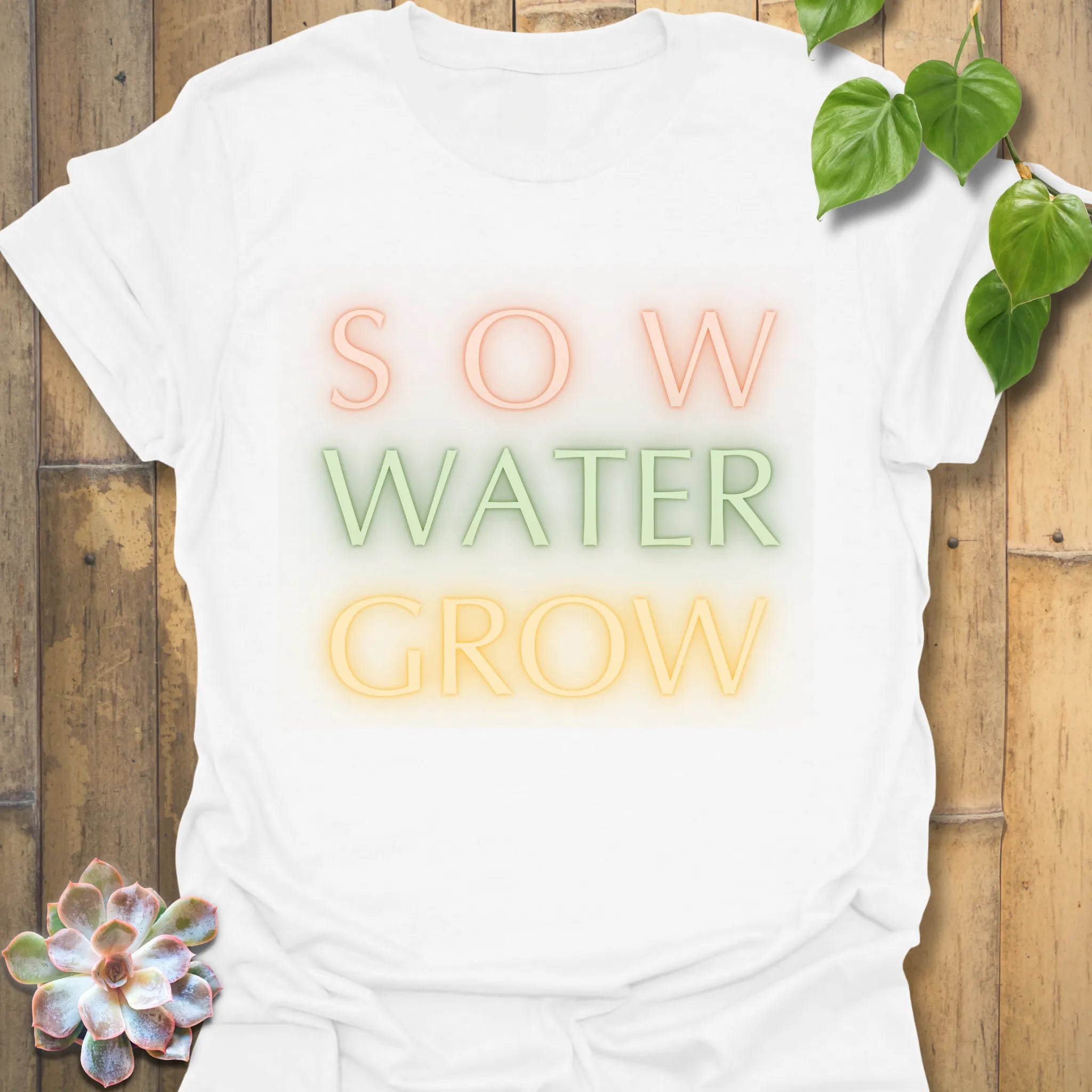 White t-shirt featuring the design Sow Water Grow printed with a plant and watering can graphic.