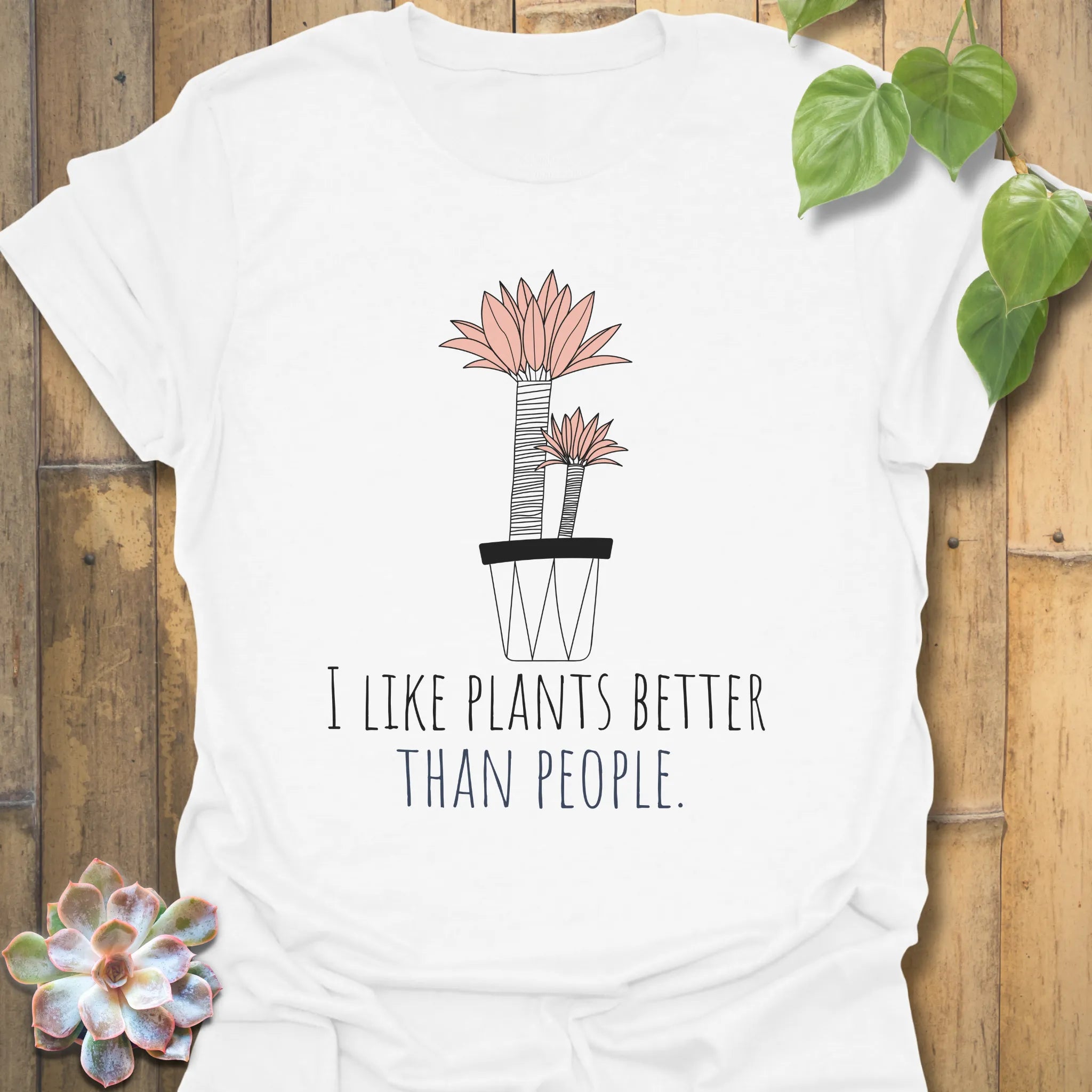 White t-shirt with the design “I like plants better than people” and a flower in a pot graphic