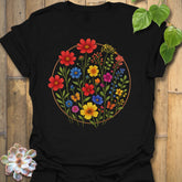 Black “Circle of Flowers” T-shirt with a bright circular wildflower design in red, yellow, blue, and pink tones — vibrant nature-inspired print on Gildan 64000.