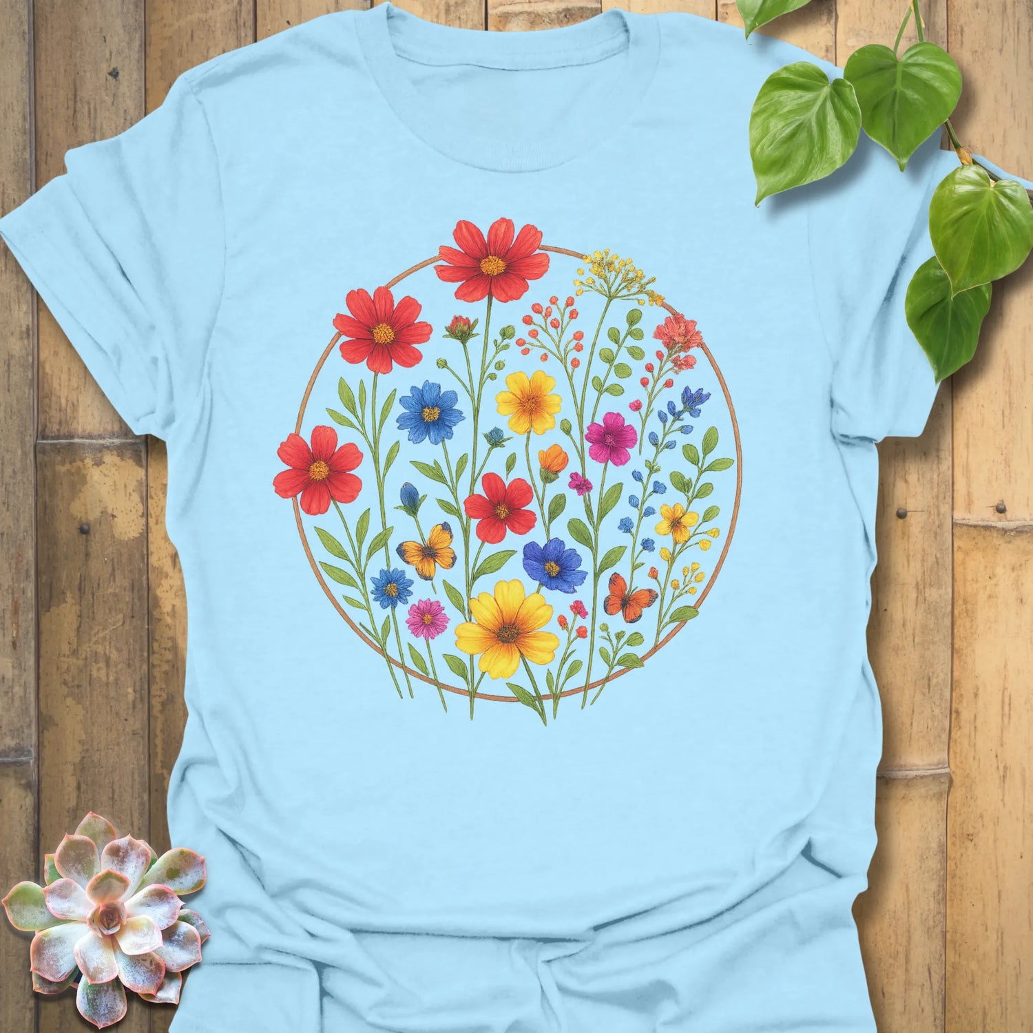 Light blue “Circle of Flowers” T-shirt with multicoloured floral circle design — cheerful botanical print on soft Gildan 64000 cotton.