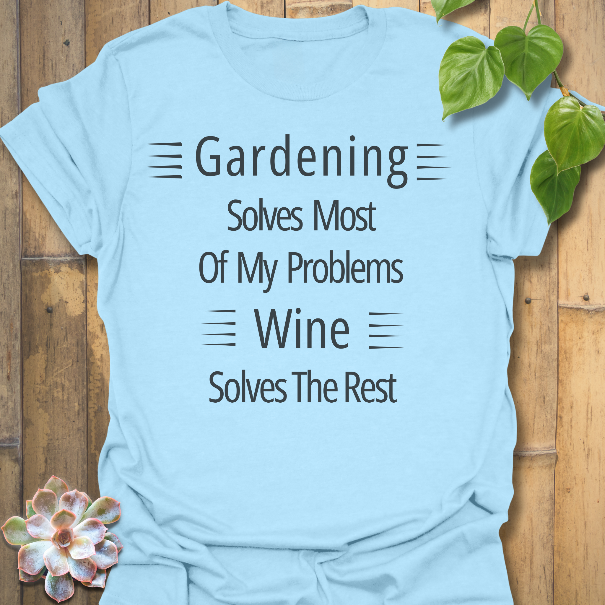 Gildan 64000 Light Blue unisex t-shirt displaying the phrase ‘Gardening solves most of my problems, wine solves the rest’ in white text. Soft cotton blend.