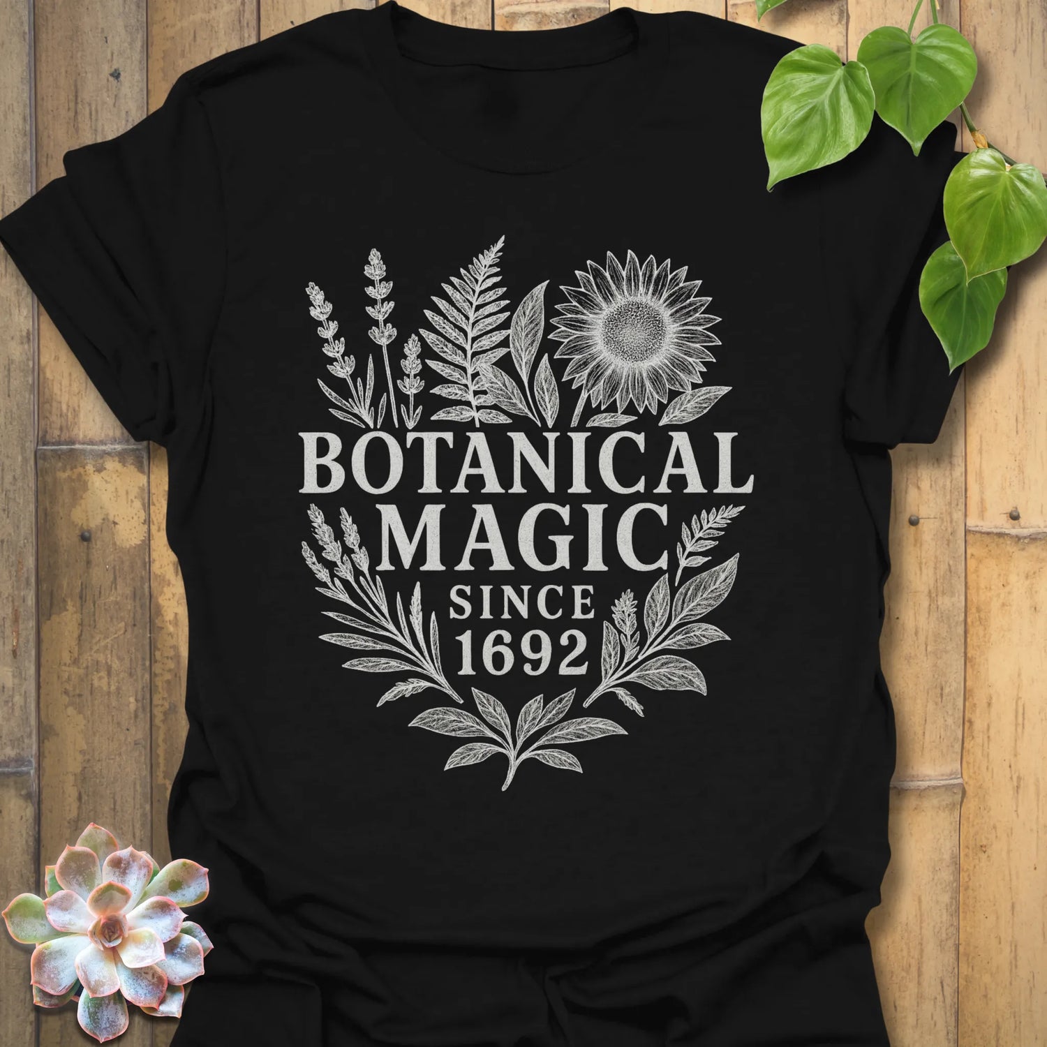 Black t-shirt featuring the design Botanical Magic printed in bold letters, floral graphic tee.