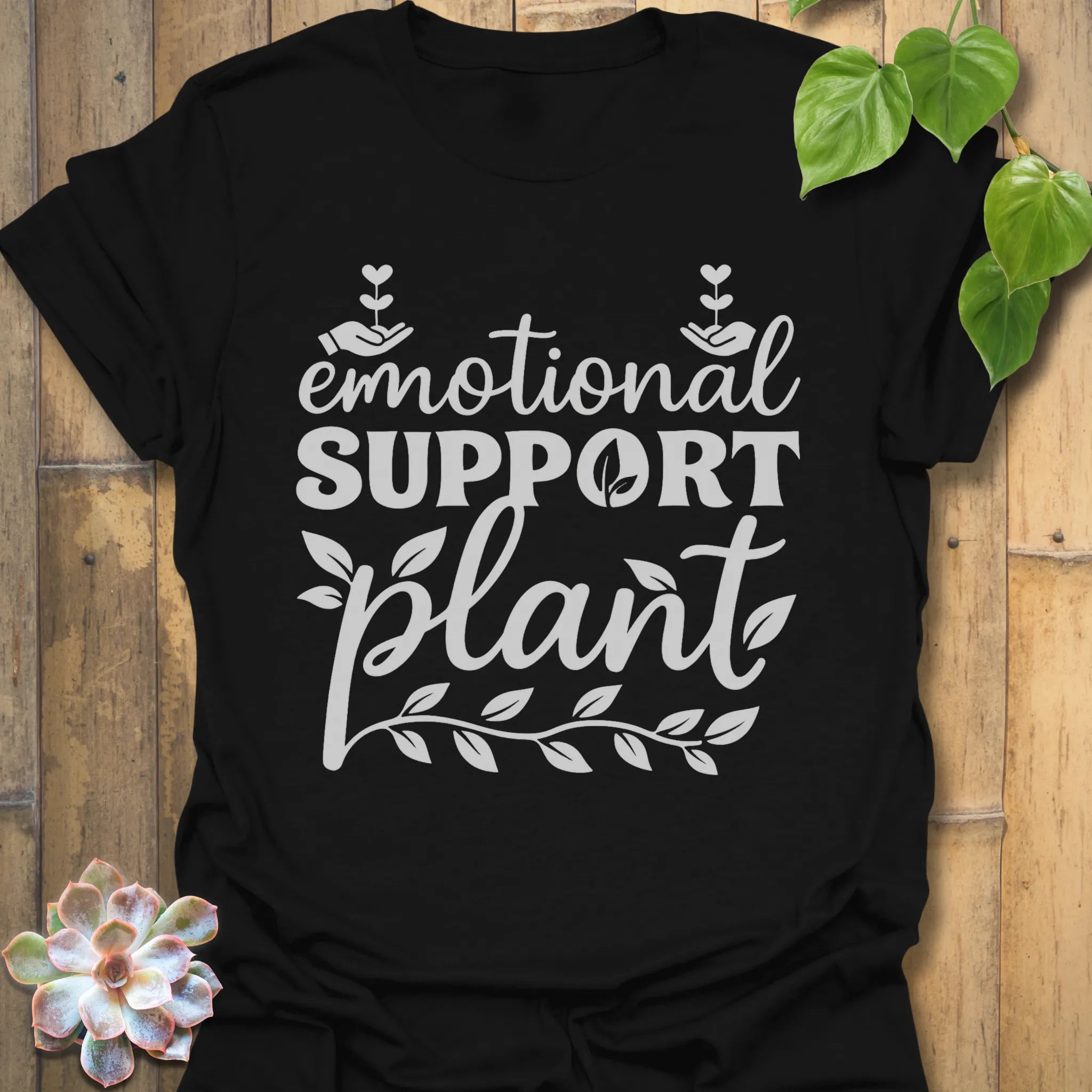 Black t-shirt featuring the design Emotional Support printed in bold letters, plant wellness graphic shirt.