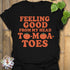 Black t-shirt featuring the design Feeling Good printed in bold orange letters, feel-good graphic shirt.