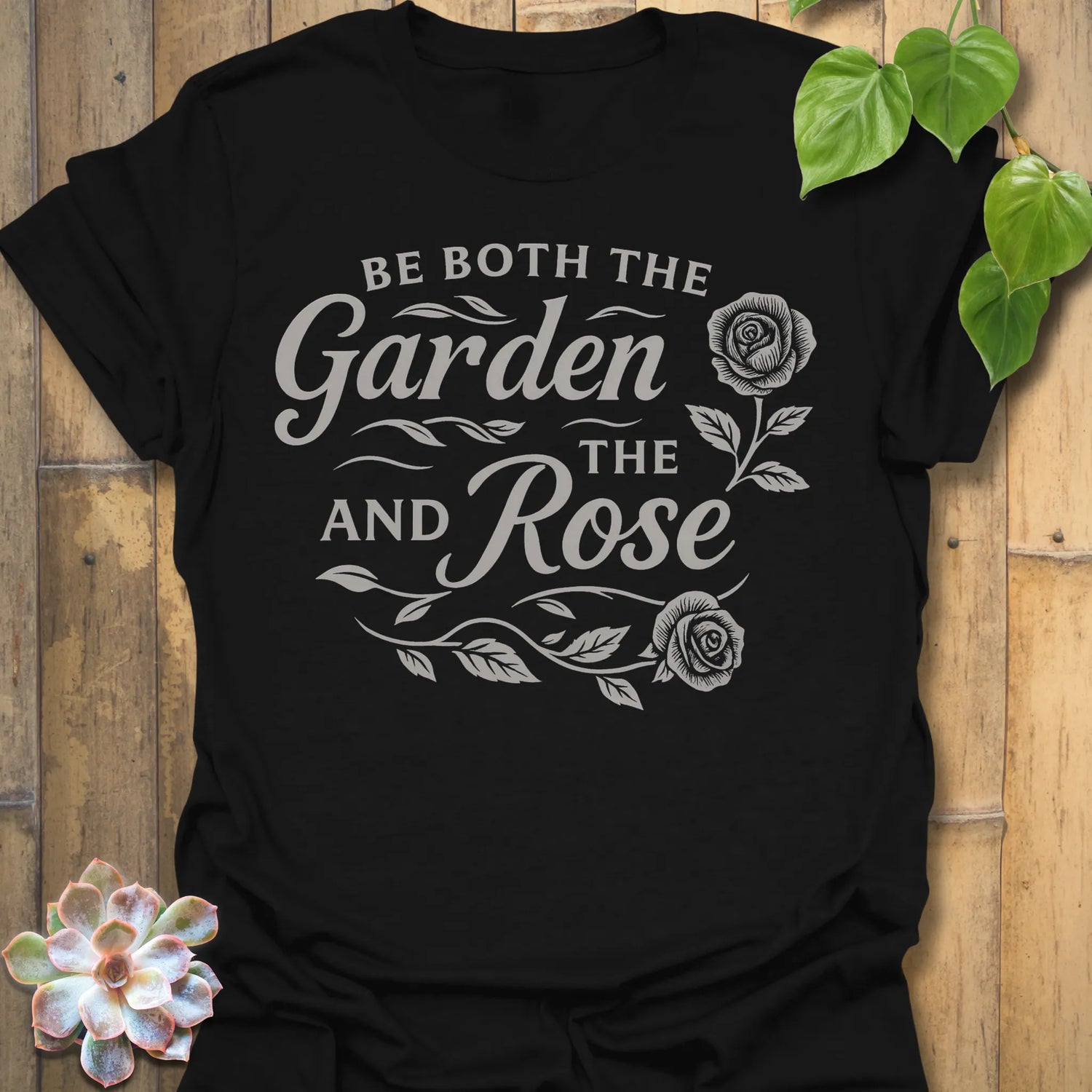 Black t-shirt featuring the design Garden And The Rose printed in soft floral tones, stylish plant lover shirt.