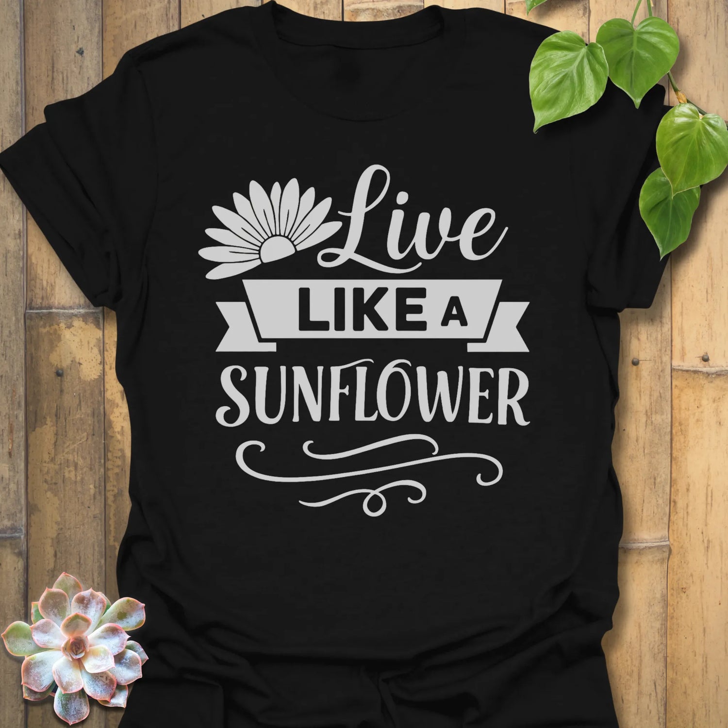 Black t-shirt featuring the design Live Like A Sunflower printed in bold black letters, sunflower lover shirt.